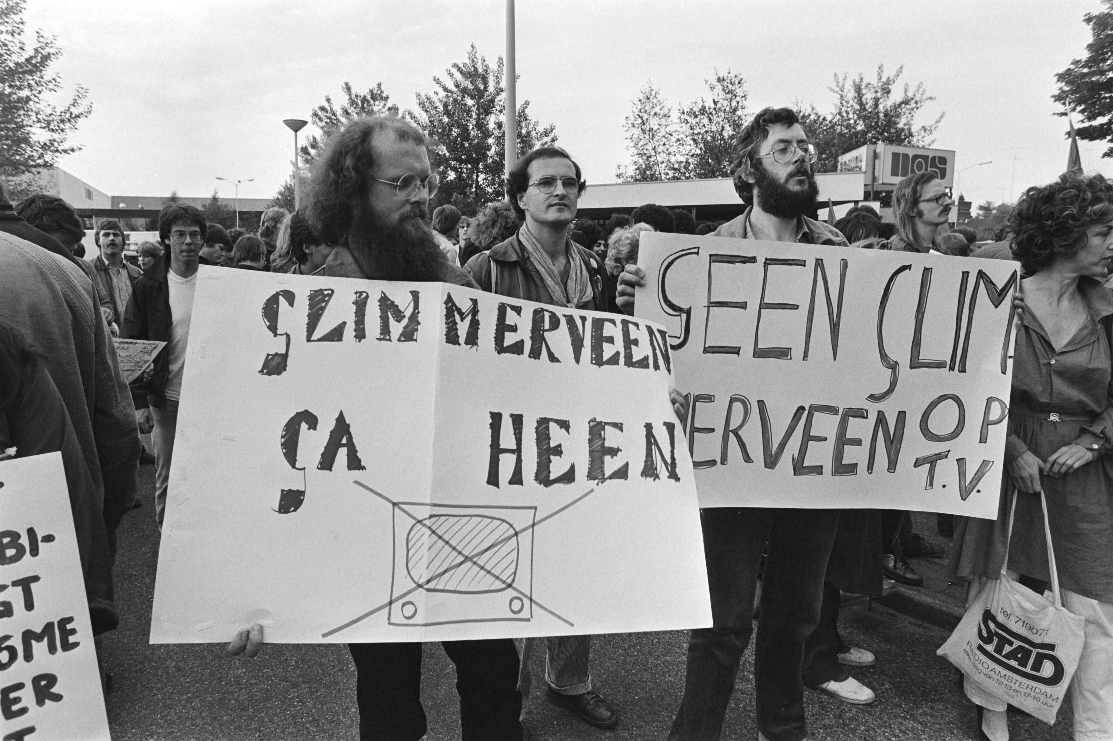 Fotocollectie Anefo — Dem. voor NOS-omroepkwartier in Hilversum tegen zendtijd Ned. Volksunie en Centrumpartij, borden "Glimmerveen ga heen" — Foto: Dijk, Hans van / Anefo. Licentie: Set B: Rechtenvrij / Publiek Domein. Bron: Nationaal Archief. http://hdl.handle.net/10648/acfbdd9e-d0b4-102d-bcf8-003048976d84