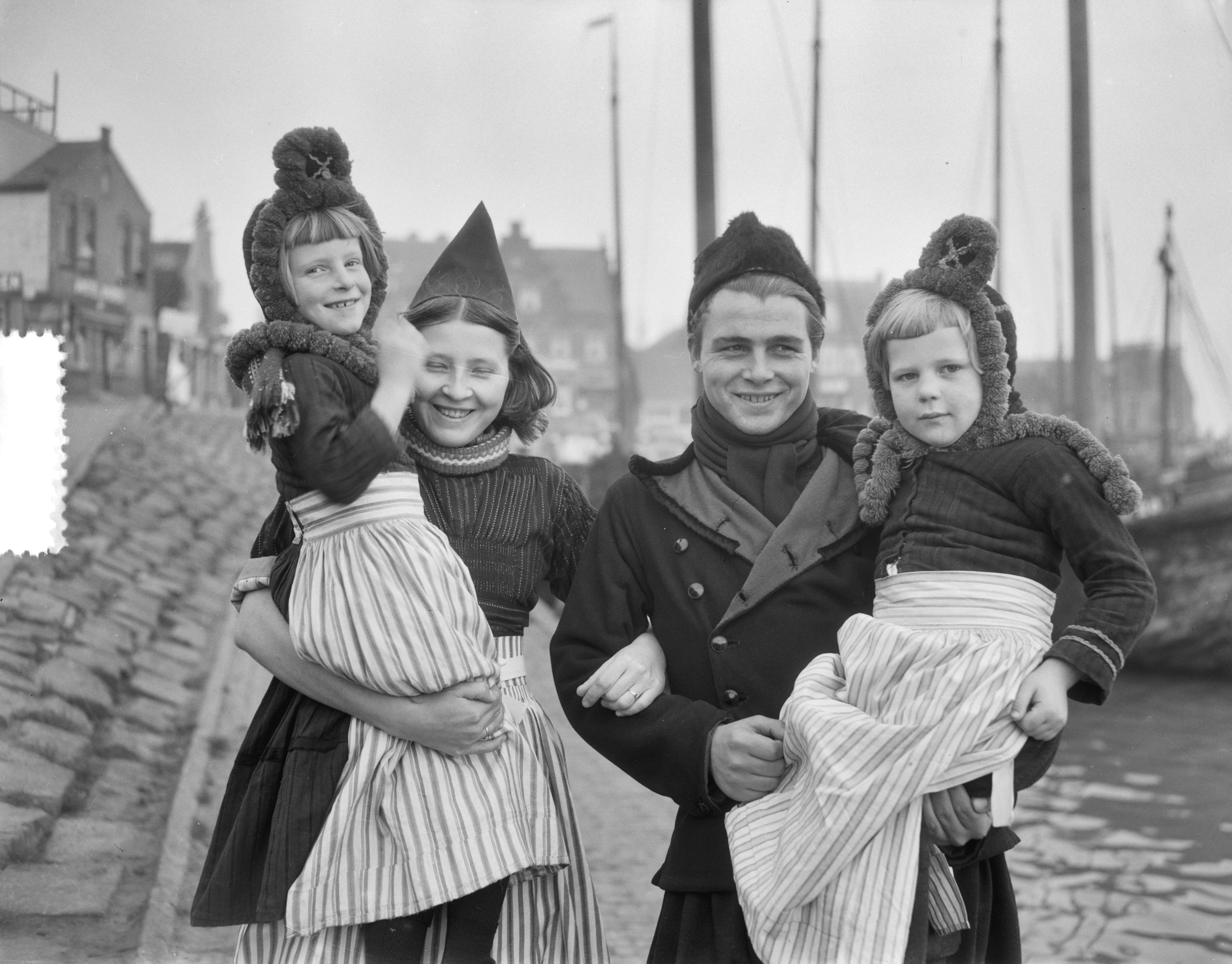 Opnamen in Volendam (familie) kinderspel — Opnamen in Volendam. Gezin in klederdracht [man en voruw en twee dochters] — Foto: Duinen, G.W. van / Anefo. Licentie: Set B: Rechtenvrij / Publiek Domein. Bron: Nationaal Archief. http://hdl.handle.net/10648/a919b1c4-d0b4-102d-bcf8-003048976d84