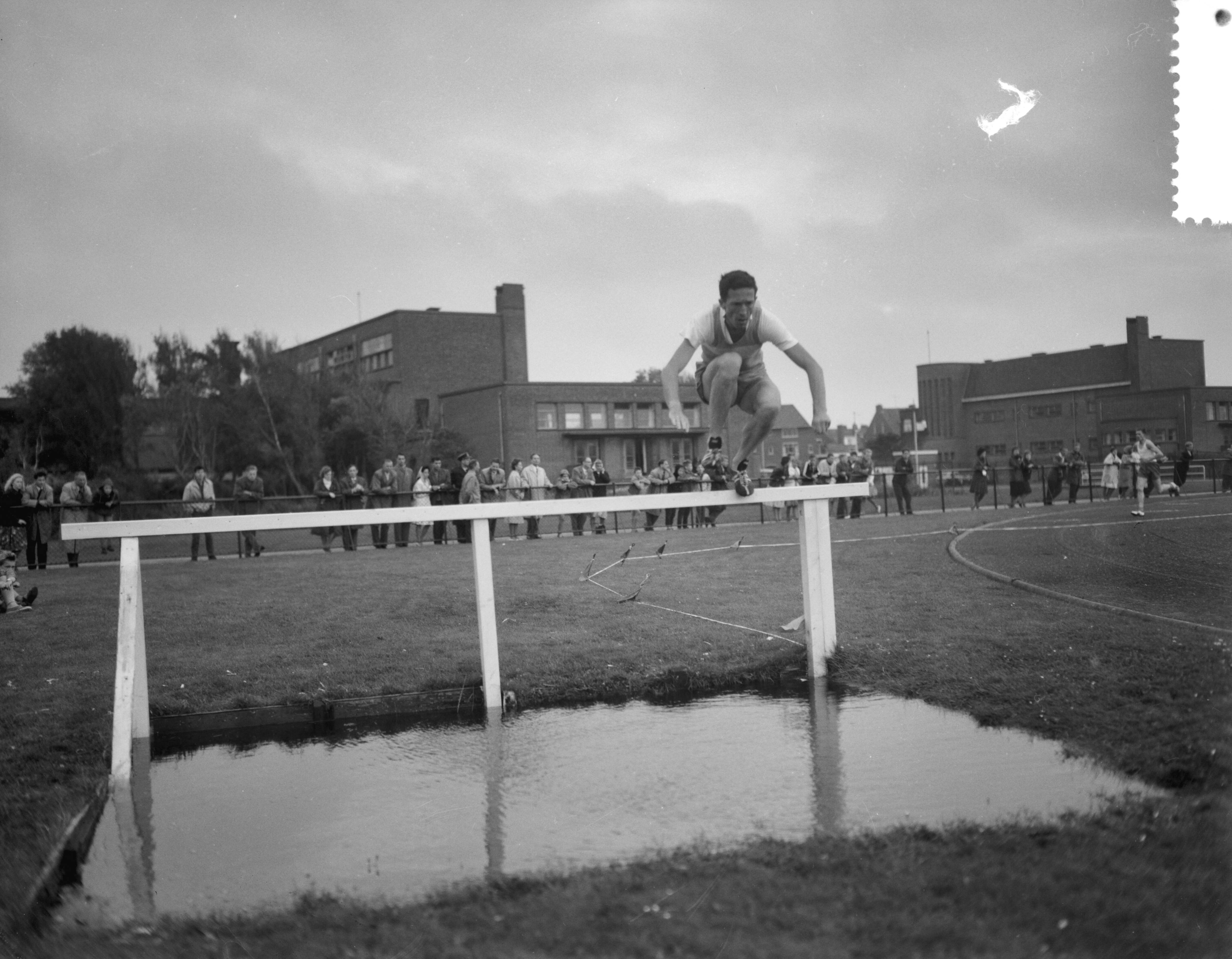 Fotocollectie Anefo — Atletiekwedstrijden Den Haag - Londen. 3000 meter steeple. Een atleet neemt de waterbak — Foto: Bilsen, Joop van / Anefo. Licentie: Set B: Rechtenvrij / Publiek Domein. Bron: Nationaal Archief. http://hdl.handle.net/10648/a9dd8c7a-d0b4-102d-bcf8-003048976d84