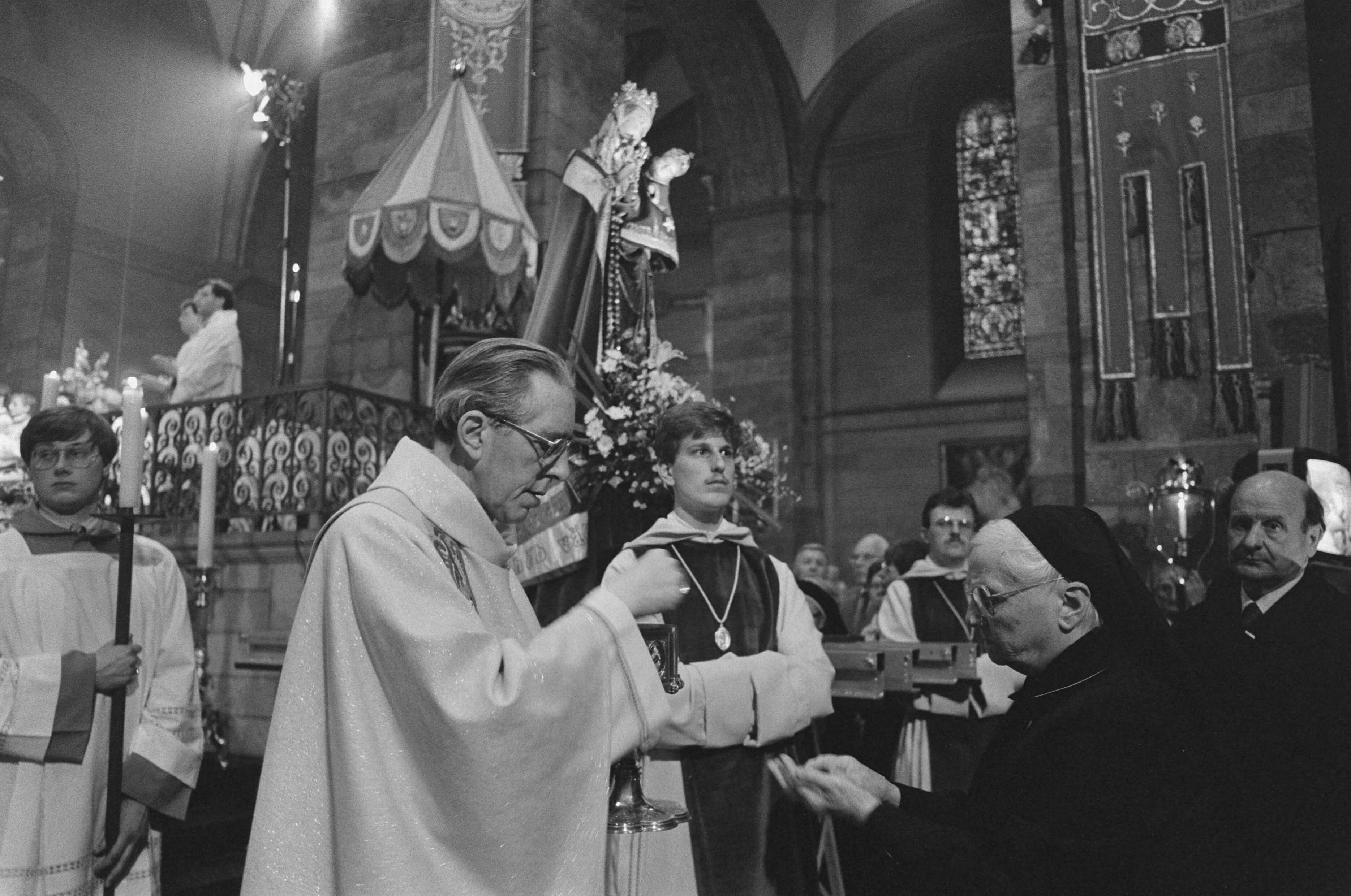 Fotocollectie Anefo — Gebedsdienst Paus J. P. II op groot projectiescherm voo Onze Lieve Vrouwebasiliek in Maastricht; bisschop Gijsen deelt hosties uit. — Foto: Gerrits, Roland / Anefo. Licentie: Set B: Rechtenvrij / Publiek Domein. Bron: Nationaal Archief. http://hdl.handle.net/10648/ad6143a0-d0b4-102d-bcf8-003048976d84