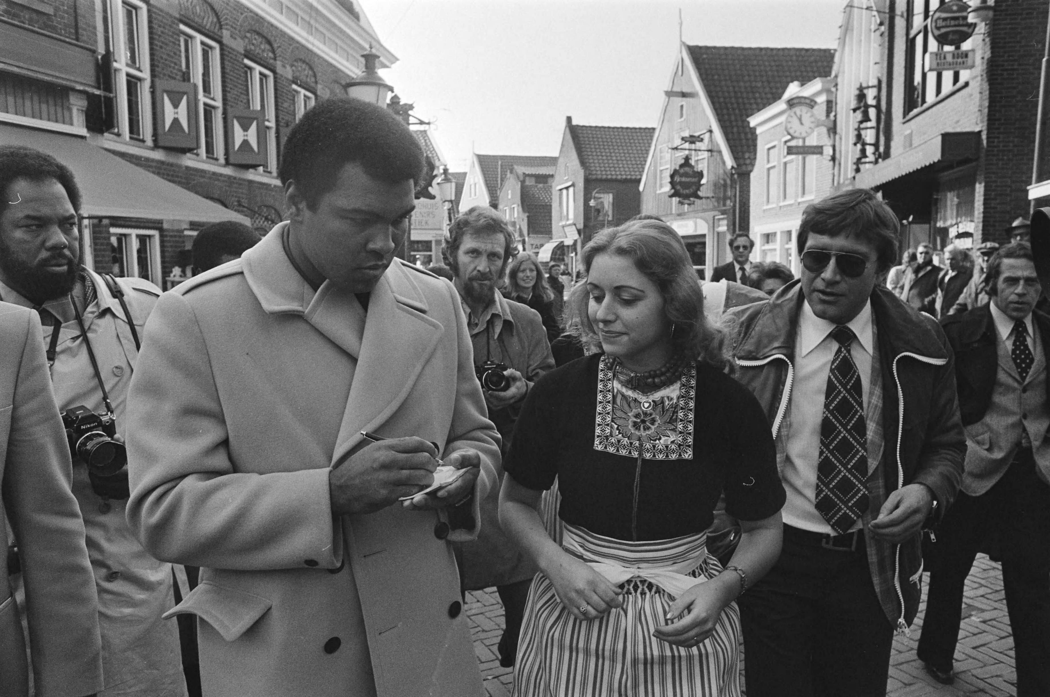 Fotocollectie Anefo — Mohammed Ali bezoekt Volendam; Ali deelt handtekeningen uit aan Volendamse meisjes — Foto: Verhoeff, Bert / Anefo. Licentie: Set B: Rechtenvrij / Publiek Domein. Bron: Nationaal Archief. http://hdl.handle.net/10648/ac7ec994-d0b4-102d-bcf8-003048976d84