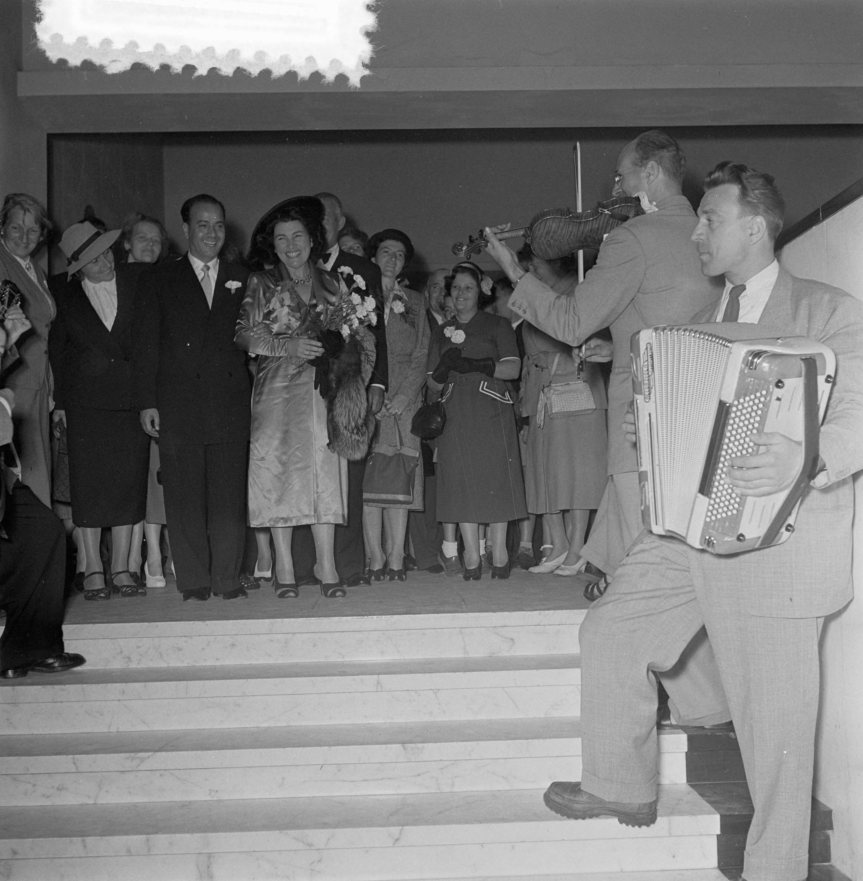 Fotocollectie Anefo — Huwelijk van Maarten Kapteyn en Jetty Cantor in Hilversum. Haar eigen Napolitaanse orkest speelt de herkenningsmedaille een aubade — Foto: Noske, J.D. / Anefo. Licentie: Set B: Rechtenvrij / Publiek Domein. Bron: Nationaal Archief. http://hdl.handle.net/10648/a911fc54-d0b4-102d-bcf8-003048976d84