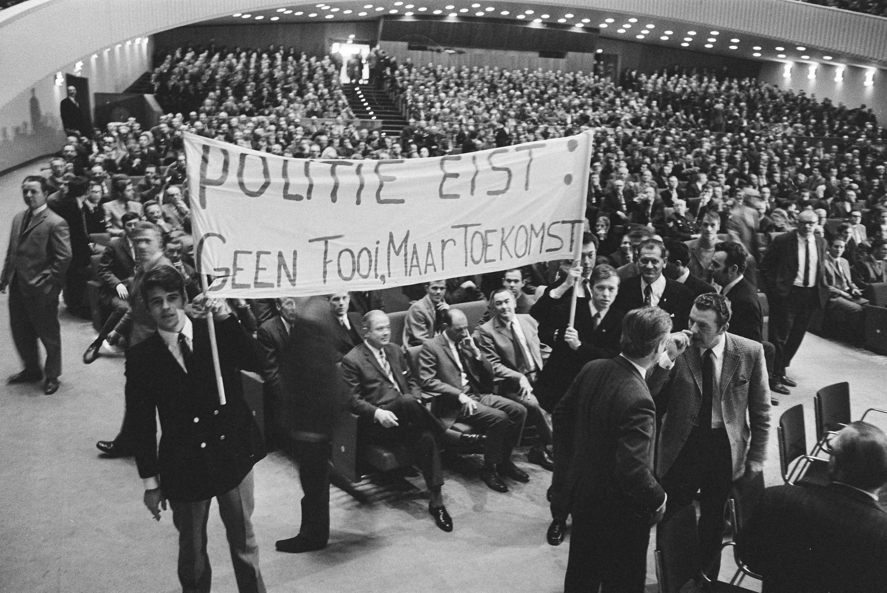 Fotocollectie Anefo — Protestvergadering van 2.000 politiemannen in Congresgebouw Den Haag ; o.a. voor betere salariering overzicht met bord — Foto: Verhoeff, Bert / Anefo. Licentie: Set B: Rechtenvrij / Publiek Domein. Bron: Nationaal Archief. http://hdl.handle.net/10648/abac5428-d0b4-102d-bcf8-003048976d84