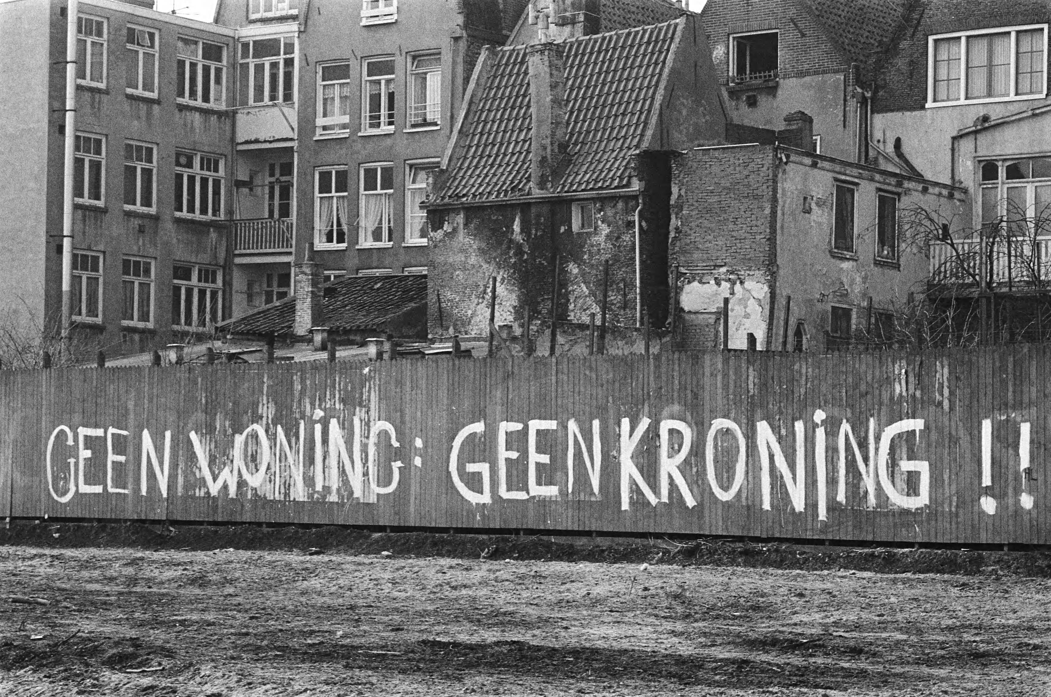 Fotocollectie Anefo — Tekst: "Geen woning, geen kroning" op schutting Haarlemmer Houttuinen — Foto: Suyk, Koen / Anefo. Licentie: Set B: Rechtenvrij / Publiek Domein. Bron: Nationaal Archief. http://hdl.handle.net/10648/acdd15d0-d0b4-102d-bcf8-003048976d84