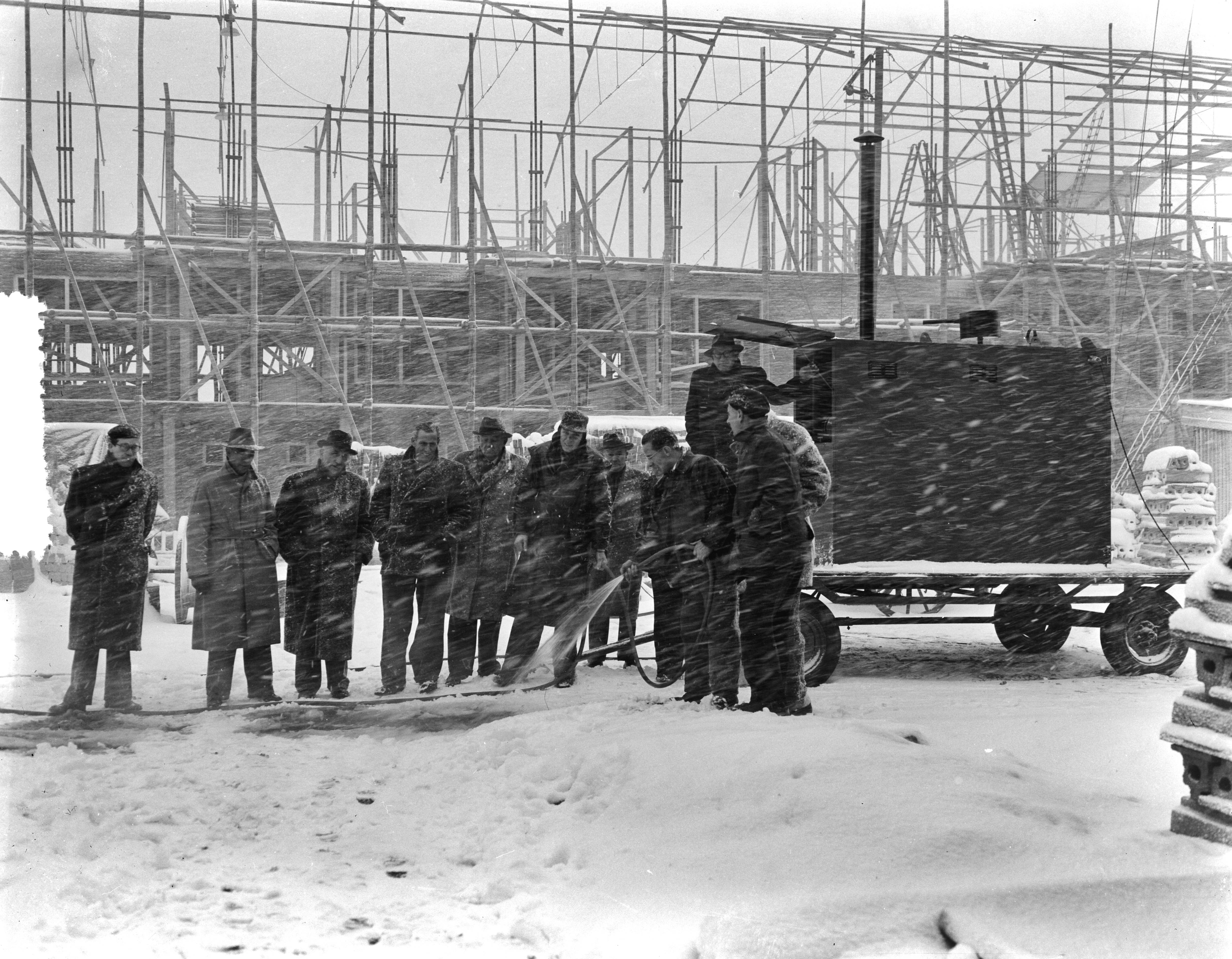 Fotocollectie Anefo — Warm water gieten voor sneeuwvrij maken op bouwplaats te Den Haag — Foto: Pot, Harry / Anefo. Licentie: Set B: Rechtenvrij / Publiek Domein. Bron: Nationaal Archief. http://hdl.handle.net/10648/a9415f62-d0b4-102d-bcf8-003048976d84