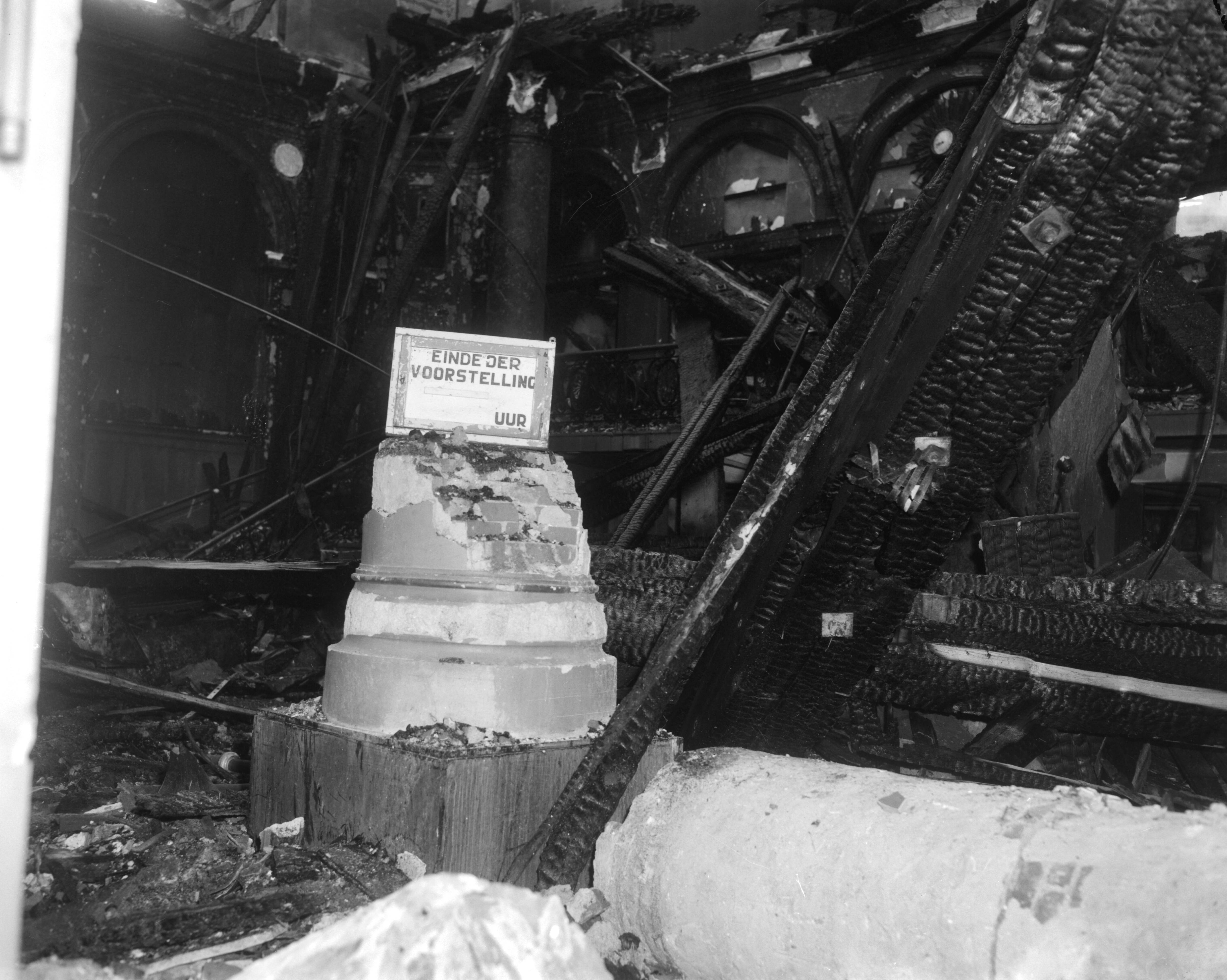Fotocollectie Anefo — Gebouw voor Kunsten en Wetenschappen in Den Haag na de brand, symbool van het einde [bordje einde der voorstelling (leeg) uur] — Foto: Bilsen, Joop van / Anefo. Licentie: Set B: Rechtenvrij / Publiek Domein. Bron: Nationaal Archief. http://hdl.handle.net/10648/aa899178-d0b4-102d-bcf8-003048976d84