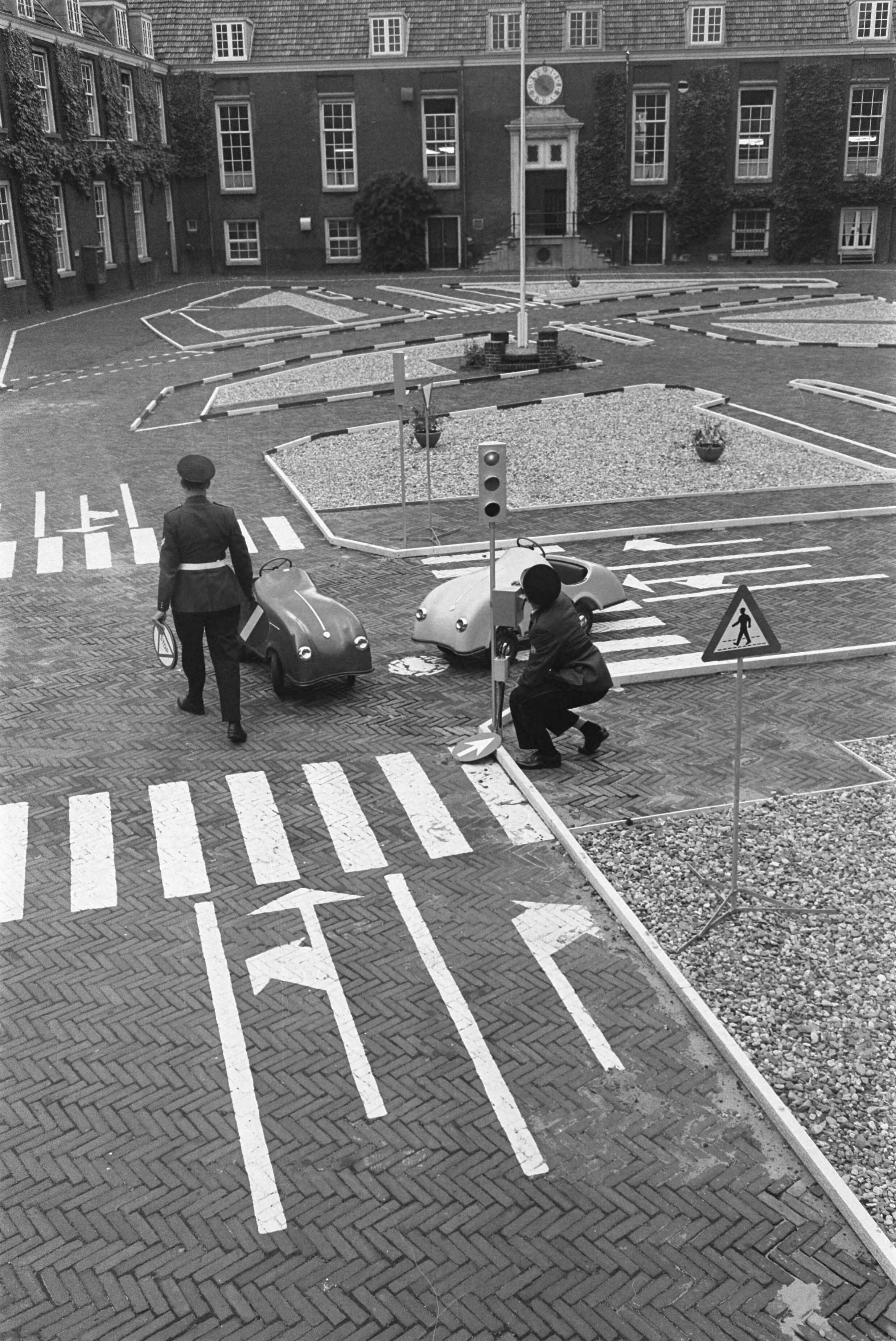 Fotocollectie Anefo — In Koudehornkazerne te Haarlem heeft de Haarlemse verkeerspolitie een verkeerstuin ingericht. Brigadier P. van Deenen en assisten-agent Van Hurk leggen de laatste hand aan de verkeerstuin, die volgens plan in september geopend wordt — Foto: Pot, Harry / Anefo. Licentie: Set B: Rechtenvrij / Publiek Domein. Bron: Nationaal Archief. http://hdl.handle.net/10648/aa4346b4-d0b4-102d-bcf8-003048976d84