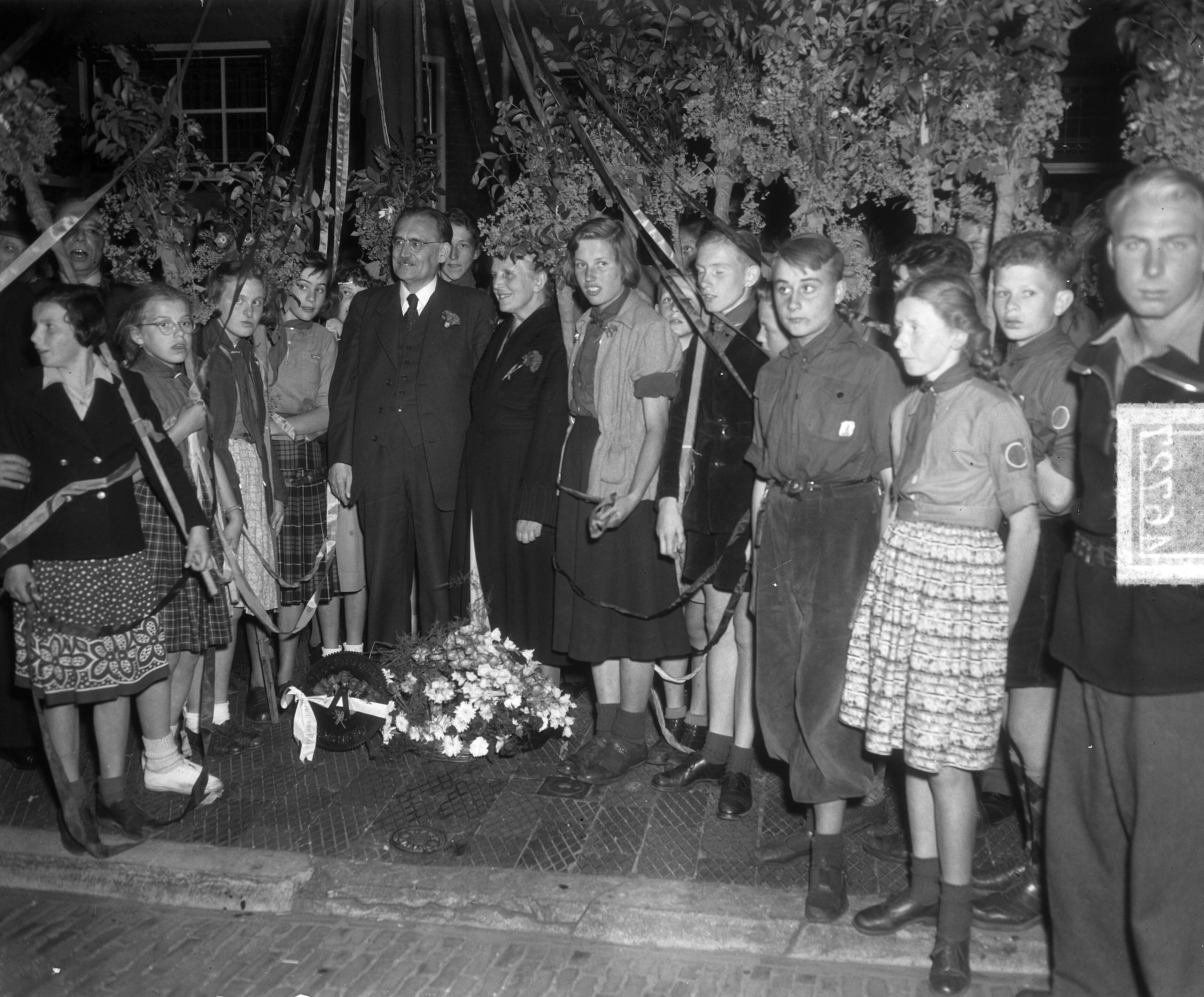 Dr. W. Drees 65 jaar. Huldiging bij zijn woning aan de Beekstraat te Den Haag — Dr. W. Drees 65 jaar. Huldiging bij zijn woning aan de Beekstraat te Den Haag. W. Drees en echtgenote omgeven door jongeren — Foto: Duinen, H. van / Anefo. Licentie: Set B: Rechtenvrij / Publiek Domein. Bron: Nationaal Archief. http://hdl.handle.net/10648/a8ecbd86-d0b4-102d-bcf8-003048976d84