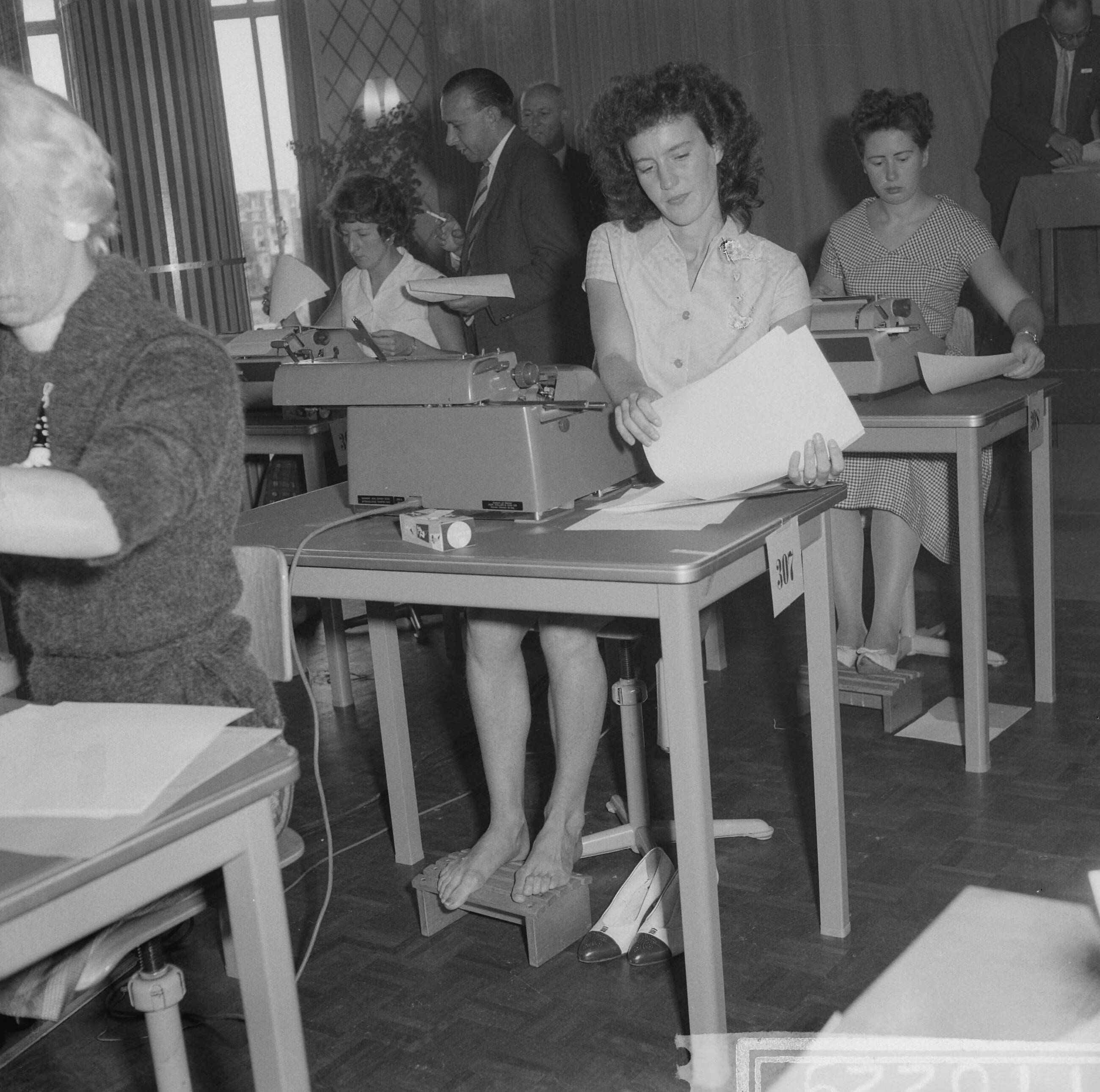 Fotocollectie Anefo — Nationaal kampioenschap machineschrijven te Den Haag, mejuffrouw I. A. Meyer uit Vught tikt op blote voeten — Foto: Lindeboom, Henk / Anefo. Licentie: Set B: Rechtenvrij / Publiek Domein. Bron: Nationaal Archief. http://hdl.handle.net/10648/a9ba3e78-d0b4-102d-bcf8-003048976d84