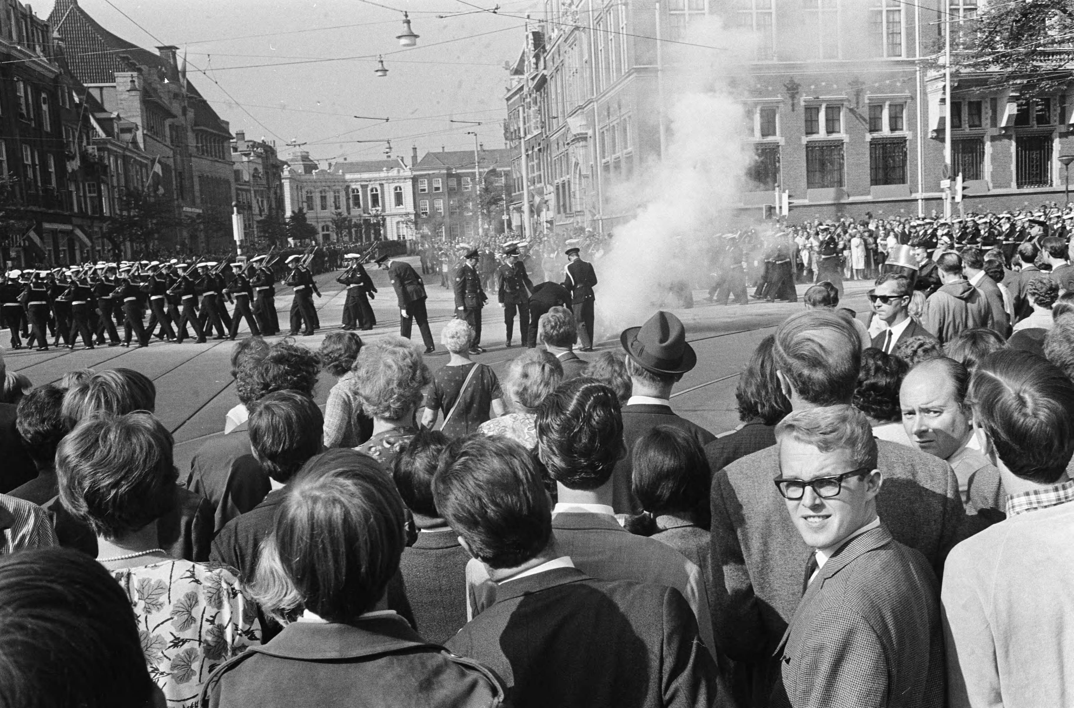Protesterende Amsterdamse Provo's tijdens Prinsjesdag 1966 in Den Haag — Ontploffende rookbom binnen de afzetting — Foto: Fotograaf Onbekend / Anefo. Licentie: Set B: Rechtenvrij / Publiek Domein. Bron: Nationaal Archief. http://hdl.handle.net/10648/aafd40dc-d0b4-102d-bcf8-003048976d84