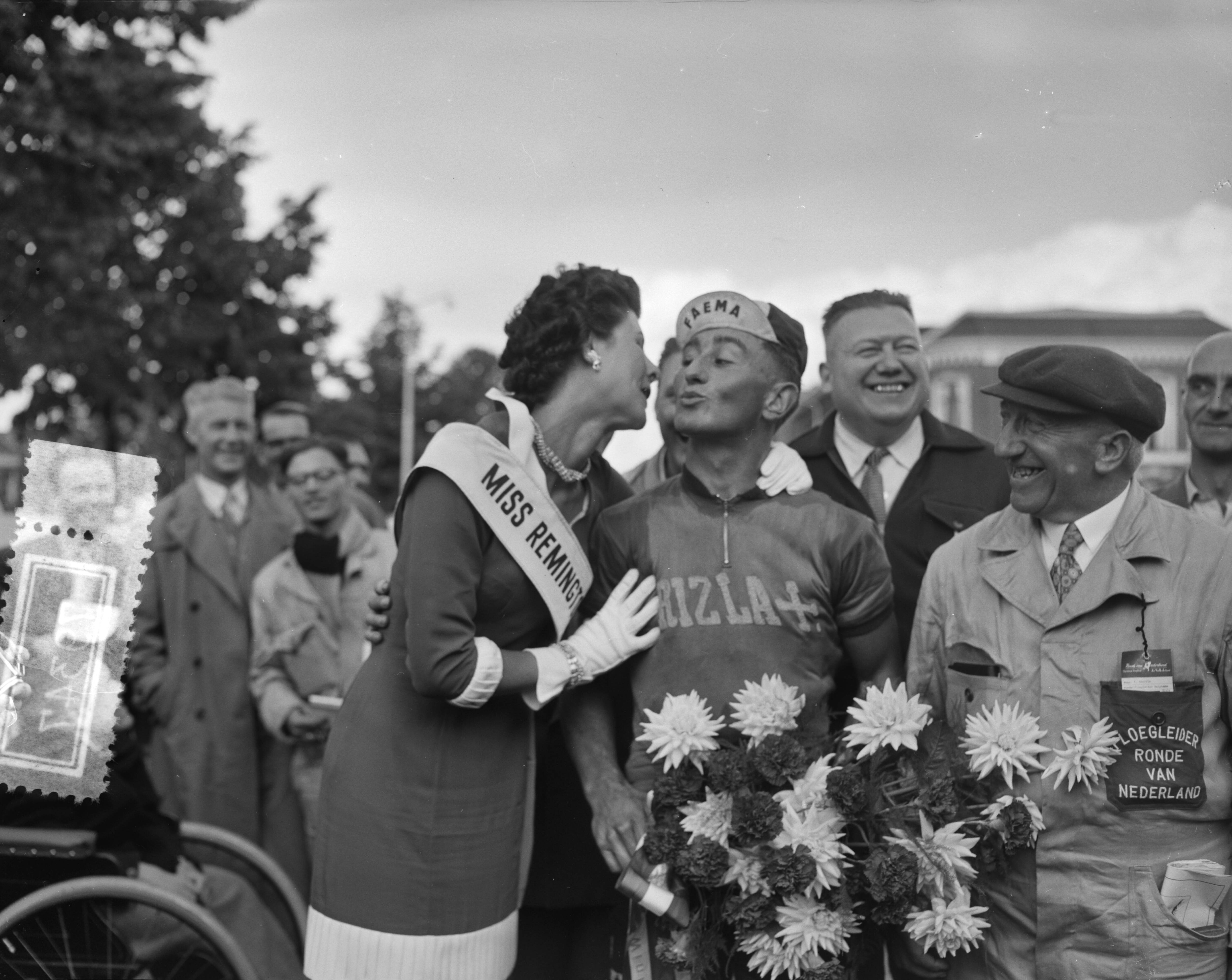 Fotocollectie Anefo — Ronde van Nederland. 2e etappe Steenwijkerwold-Leeuwarden. Etappewinnaar de Belg Willy Vannitsen krijgt kus van Miss Remington. Rechts zijn ploegleider — Foto: Bilsen, Joop van / Anefo. Licentie: Set B: Rechtenvrij / Publiek Domein. Bron: Nationaal Archief. http://hdl.handle.net/10648/a94cfb88-d0b4-102d-bcf8-003048976d84