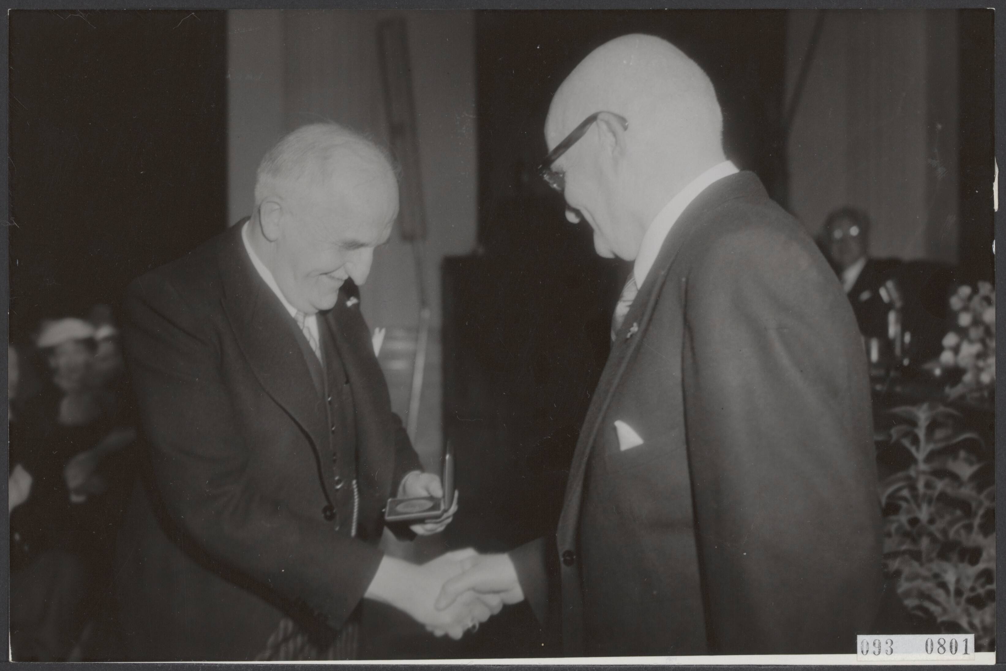 Fotocollectie Elsevier Binnenland — Afscheid van de Commissaris der Koningin in de provincie Noord-Holland, dr. J.E. baron De Vos van Steenwijk in het Gouvernementsgebouw te Haarlem. De waarnemend commissaris A.B.J. Prakken overhandigt hem de gouden medaille van de provincie Noord-Holland — Foto: Fotograaf Onbekend / Anefo. Licentie: Set B: Rechtenvrij / Publiek Domein. Bron: Nationaal Archief. http://hdl.handle.net/10648/ae2950ac-d0b4-102d-bcf8-003048976d84