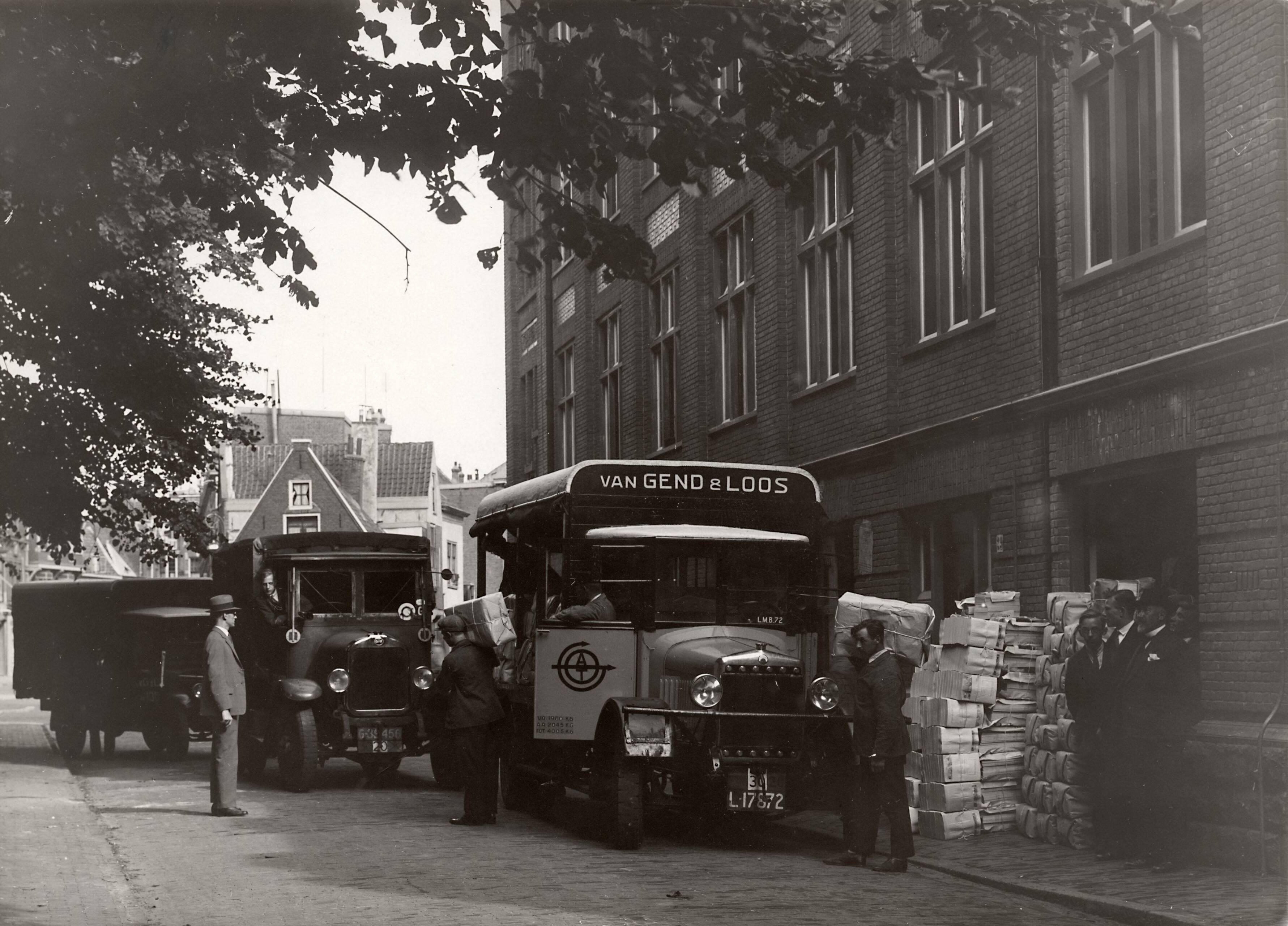 Collectie nader te bepalen — [Serie Bedrijfsvoering Spaarnestad] [vrachtwagens van Van Gend en Loos bij de expeditie van de drukkerij waar stapels tijdschriften tegen de gevel staan] — Foto: Fotograaf Onbekend / Fotobureau onbekend / Spaarnestad Photo (05887). Licentie: Set B: Rechtenvrij / Publiek Domein. Bron: Nationaal Archief. http://hdl.handle.net/10648/35429da6-42a0-a382-e063-6df0900a6686