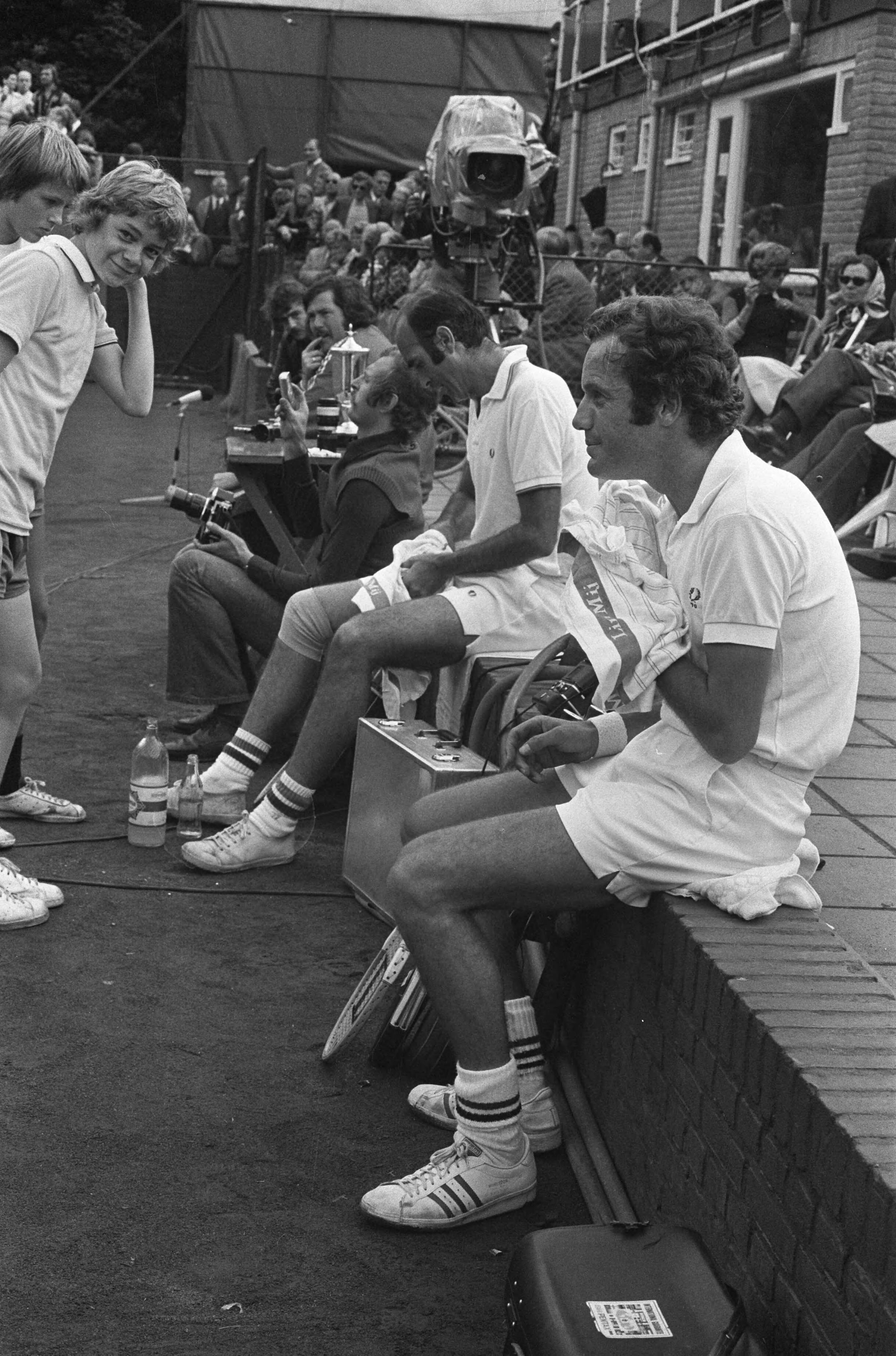 Fotocollectie Anefo — Internationale Tenniskampioenchappen Melkhuisje, Tom Okker (rechts) en Gimeno rusten — Foto: Punt, W. / Anefo. Licentie: Set B: Rechtenvrij / Publiek Domein. Bron: Nationaal Archief. http://hdl.handle.net/10648/ac323ce6-d0b4-102d-bcf8-003048976d84