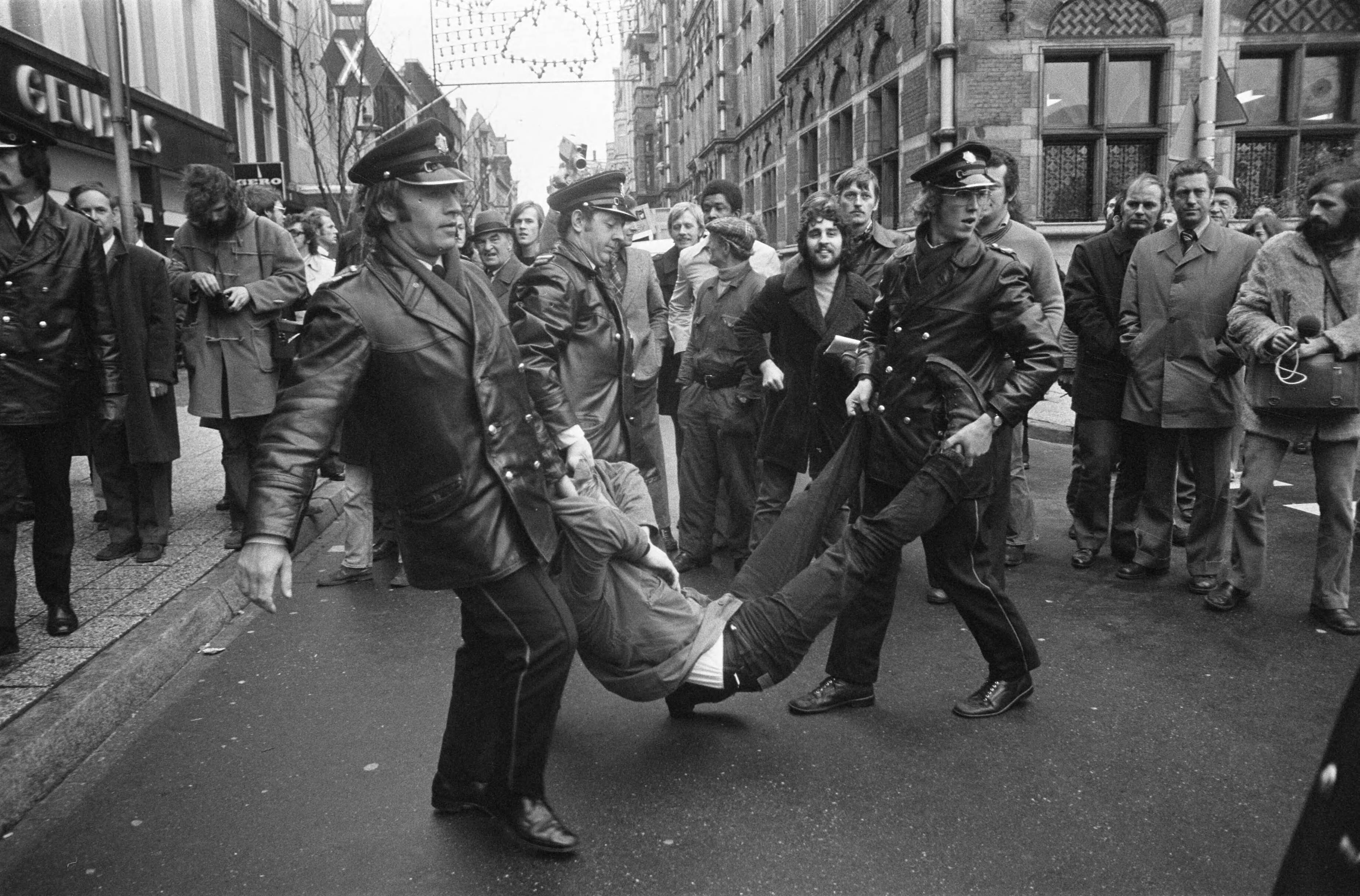 Fotocollectie Anefo — Demonstratie voor vrijlating van Kees Vellekoop (die om politieke redenen dienst weigert) voor Min. van Defensie in Den Haag ; politie draagt een demonstrant — Foto: Peters, Hans / Anefo. Licentie: Set B: Rechtenvrij / Publiek Domein. Bron: Nationaal Archief. http://hdl.handle.net/10648/ac5c25d8-d0b4-102d-bcf8-003048976d84