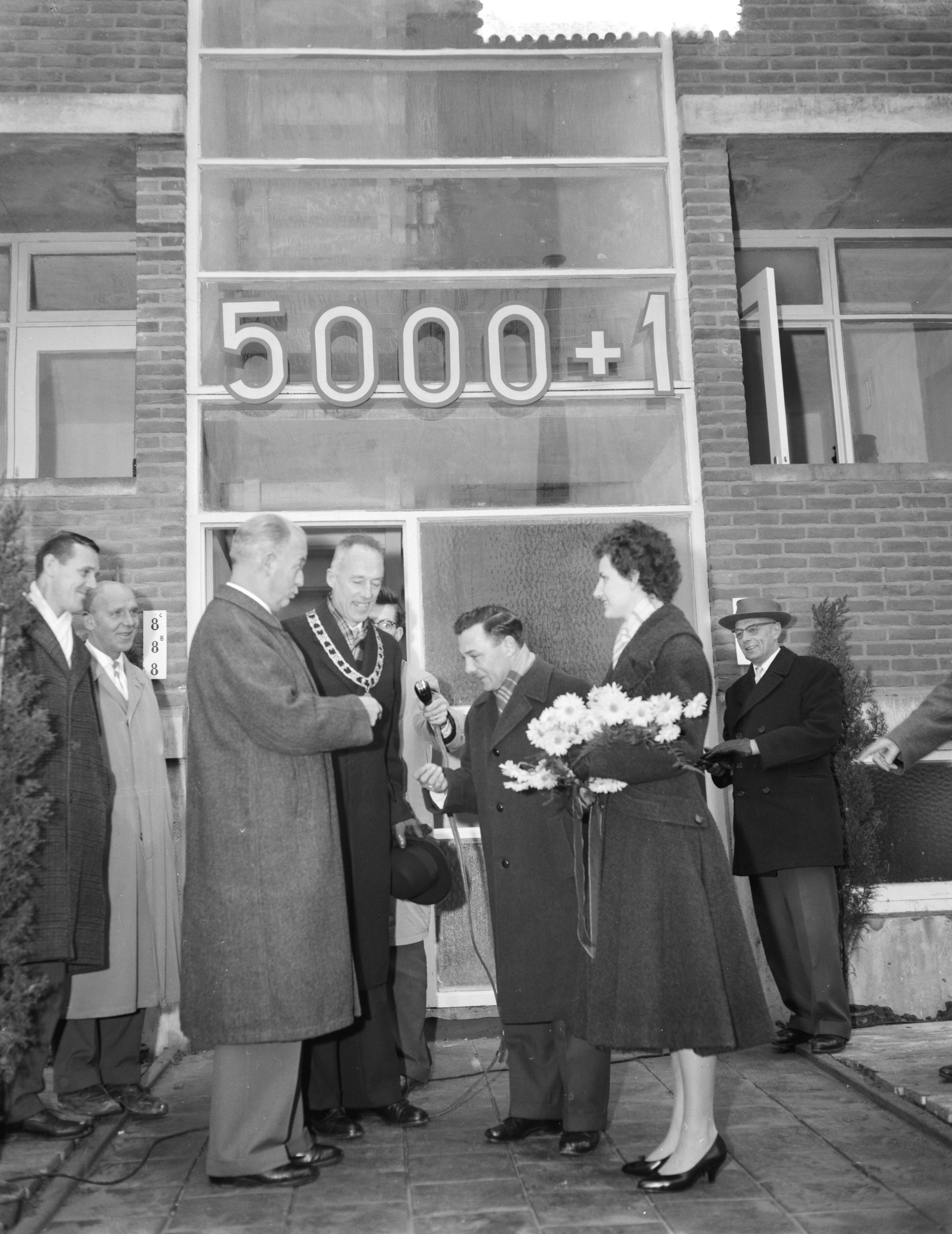 Fotocollectie Anefo — 5000ste na-oorlogse woning te Leeuwarden gereed gekomen. Betreft Beukenstraat nr. 6 in de buurt Heechterp, bewoners de familie Burger. Ir. D. Visser, hoofdingenieur-directeur van Volkshuisvesting en Bouwnijverheid in Friesland, overhandigt de sleutel. Naast hem burgemeester A.A.M. van der Meulen — Foto: Rossem, Wim van / Anefo. Licentie: Set B: Rechtenvrij / Publiek Domein. Bron: Nationaal Archief. http://hdl.handle.net/10648/a9a2bb90-d0b4-102d-bcf8-003048976d84