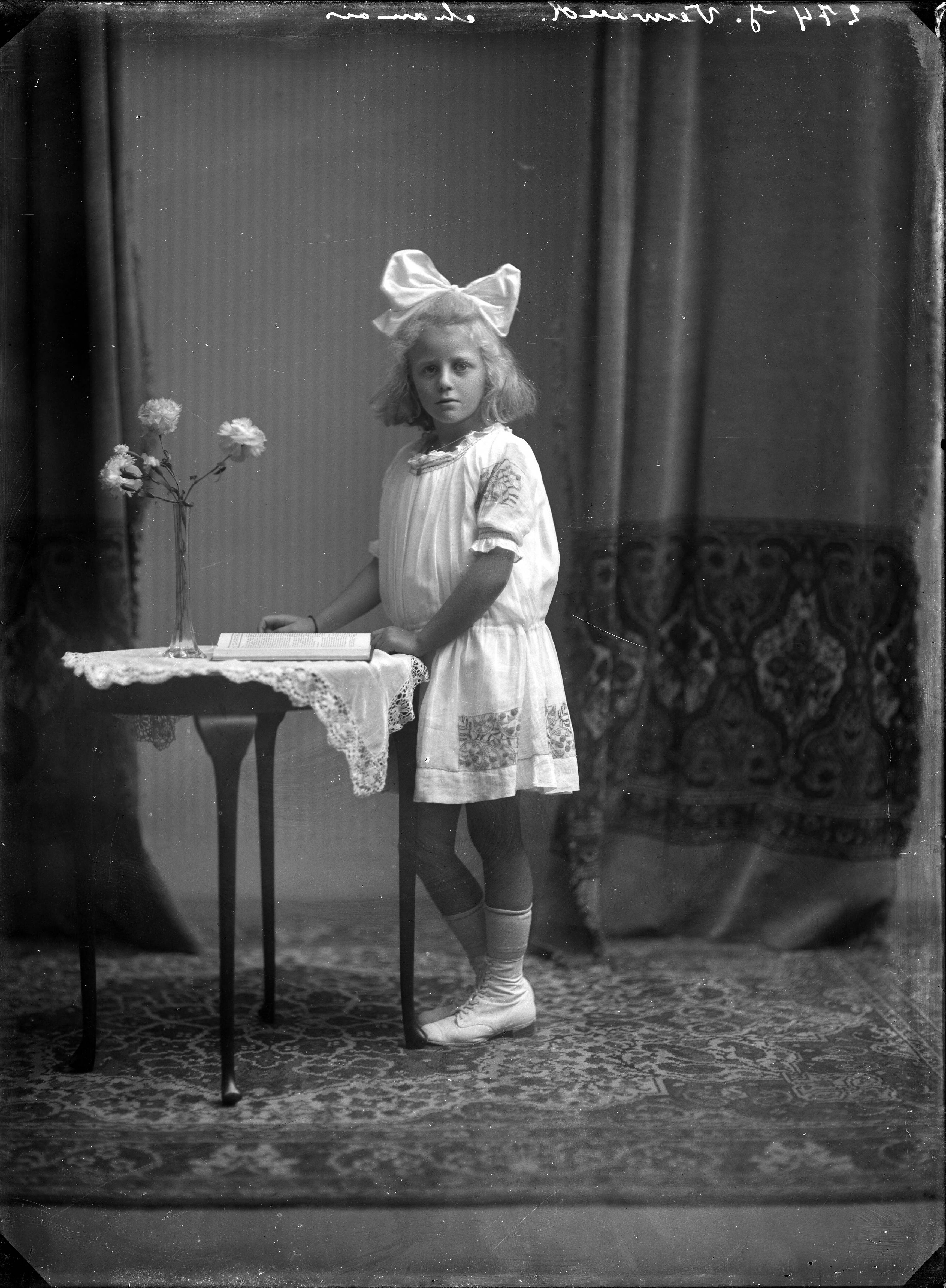 Portretten — Studio-opnames. Een klein meisje met blond haar met grote strik erin in een wit jurkje met borduursels in een huiskametsetting. Haarlem, Nederland. 1918-1930. 274 J. Verwoerd chamois — Foto: Berg, Th.C.J. van den / Spaarnestad Photo (05887). Licentie: Set B: Rechtenvrij / Publiek Domein. Bron: Nationaal Archief. http://hdl.handle.net/10648/35429da7-c622-a382-e063-6df0900a6686
