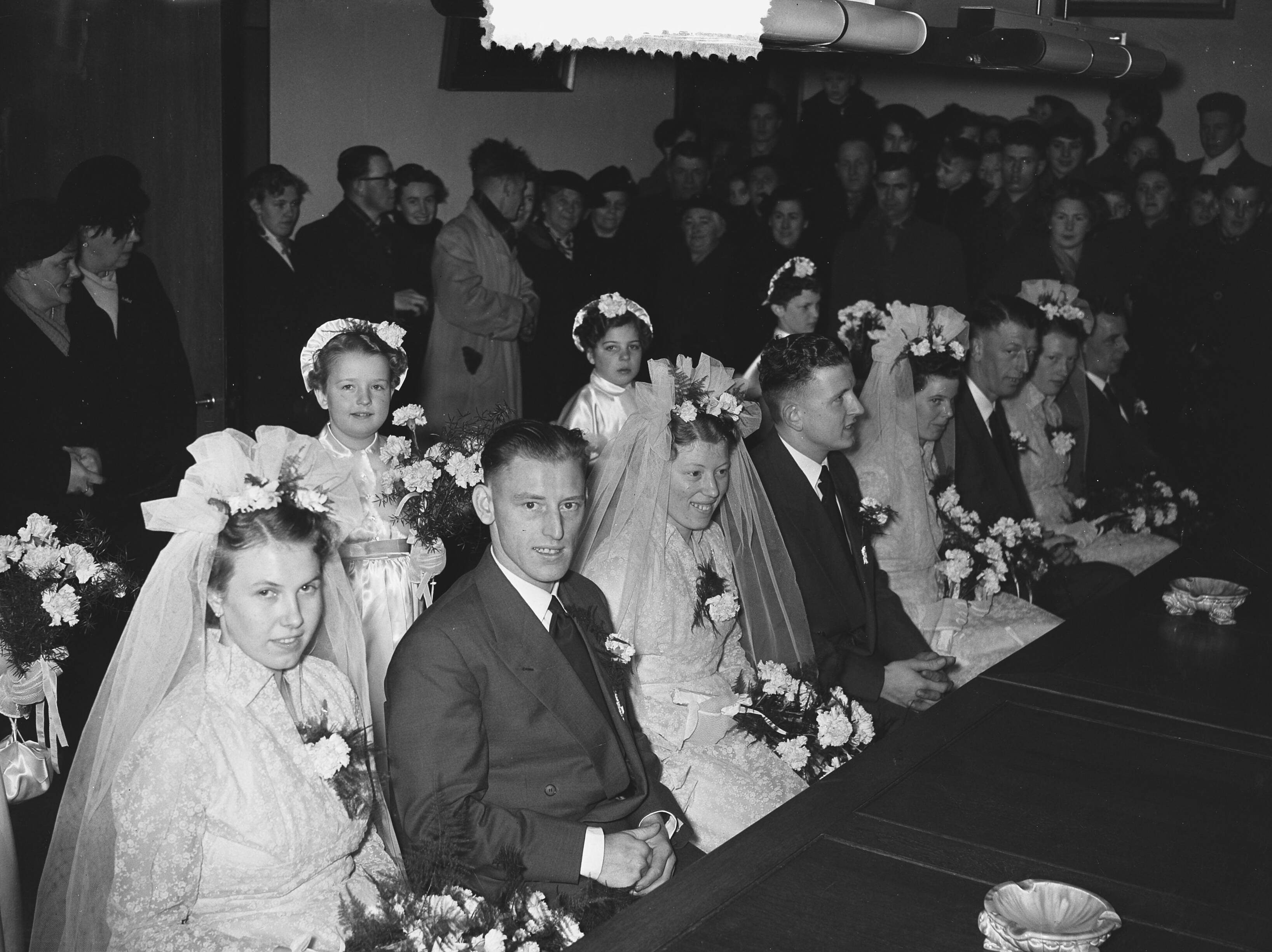Fotocollectie Anefo — Meervoudige bruiloft. Op het gemeentehuis van Leimuiden trouwden vier telgen uit het gezin Brand (15 kinderen) tegelijkertijd. Vlnr. Het zijn van links naar rechts: Toon Brand (28 jaar, chauffeur) en Catharina Lemmens, Nellie Brand (23 jaar) en Theo Obdam (timmerman), Bram Brand (26 jaar, metselaar) en Bep Könst, en Dora Brand (24 jaar) en Kees Könst (bloemist) — Foto: Pot, Harry / Anefo. Licentie: Set B: Rechtenvrij / Publiek Domein. Bron: Nationaal Archief. http://hdl.handle.net/10648/a930c9c2-d0b4-102d-bcf8-003048976d84