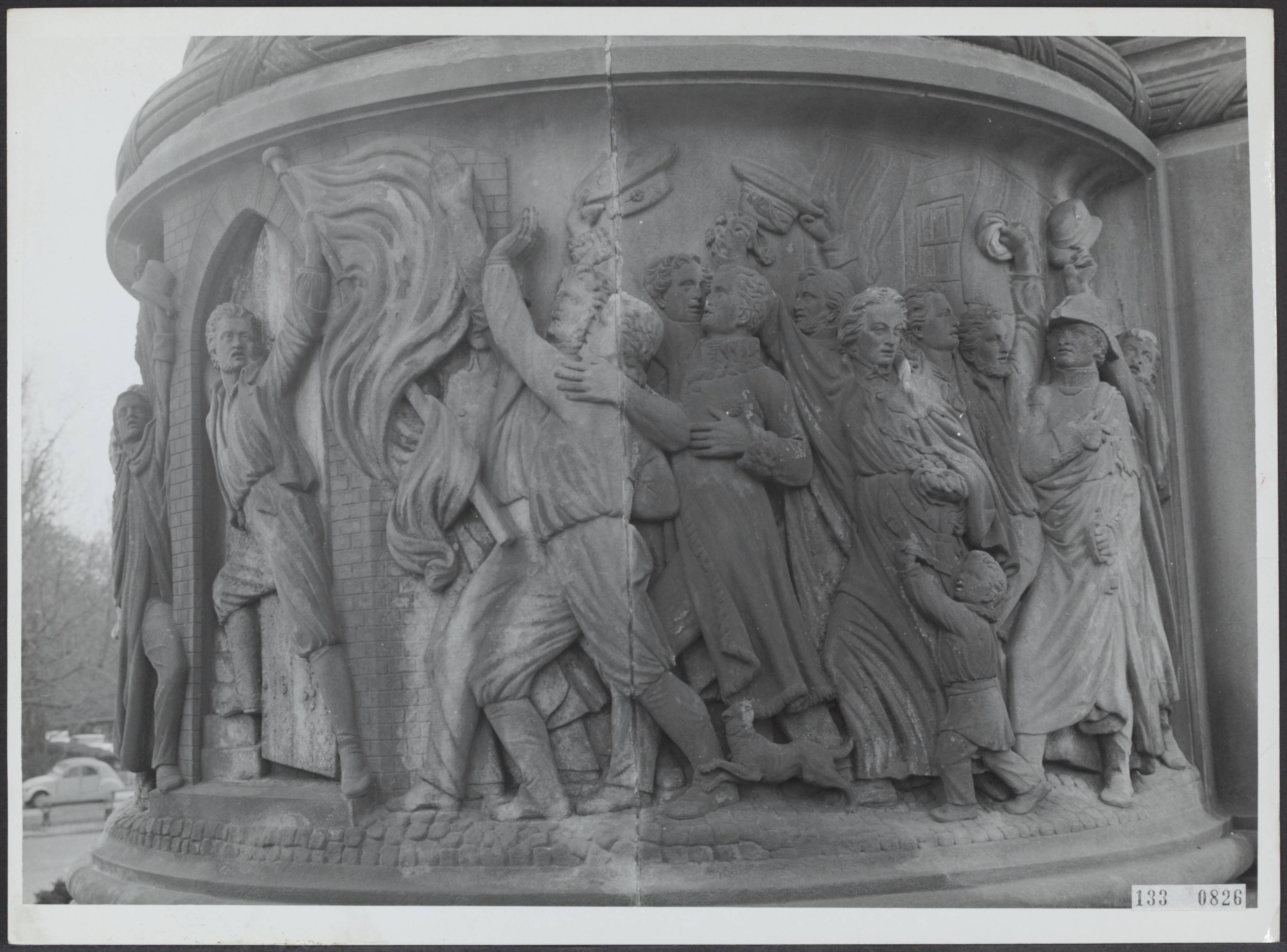 Fotocollectie Rijksvoorlichtingsdienst Eigen — Den Haag. Plein 1813: monument voor 50 jaar Nederlandse Onafhankelijkheid (1869) naar plannen van J. Ph. Koelman (sculptuur) en W.C. van der Waeyen Pieterszen (architectuur). Relief met juichende Nederlanders aan de voet van het monument — Foto: Fotodienst Gemeente Den Haag. Licentie: Set B: Rechtenvrij / Publiek Domein. Bron: Nationaal Archief. http://hdl.handle.net/10648/af5aa7e6-d0b4-102d-bcf8-003048976d84