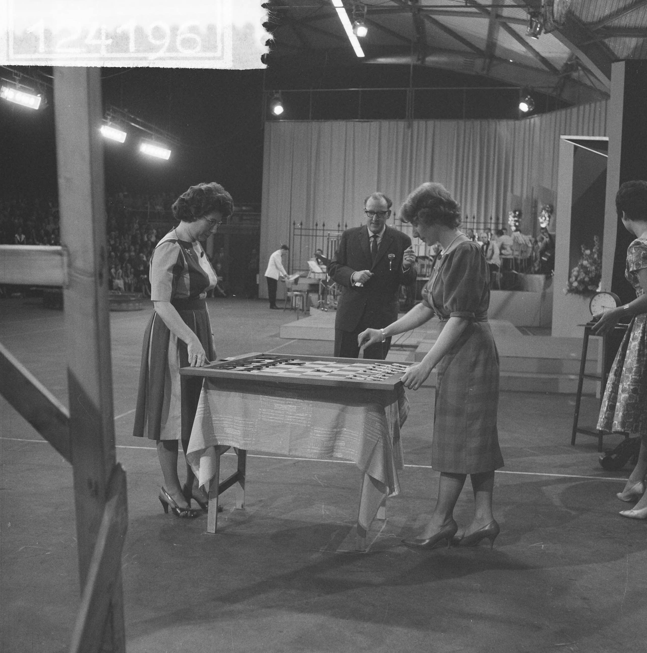 Fotocollectie Anefo — Televisieprogramma "TV-Toto" vanuit de Expohal te Hilversum. Schaakkampioene Fenny Heemskerk speelt tegen haar dochter Fenny Koomen (rechts). In het midden presentator Theo Eerdmans — Foto: Lindeboom, Henk / Anefo. Licentie: Set B: Rechtenvrij / Publiek Domein. Bron: Nationaal Archief. http://hdl.handle.net/10648/a9d34738-d0b4-102d-bcf8-003048976d84