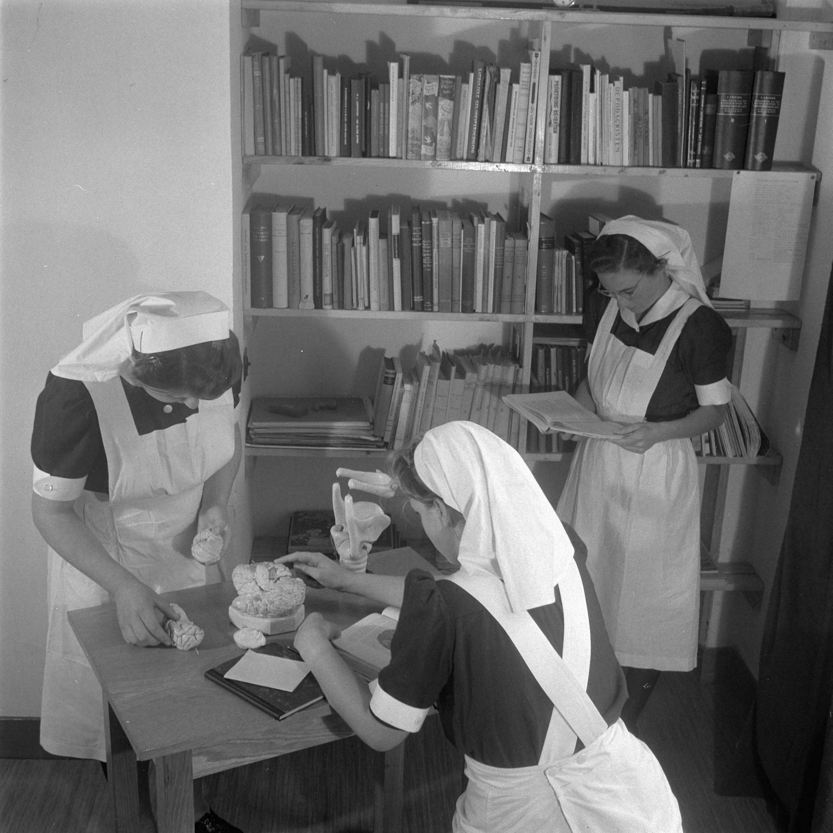 Verpleegstersschool — De eerste Katholieke Opleiding voor Verpleegkundigen in Park Vronesteyn in Voorburg. Drie verpleegkundigen zijn in de bibliotheek aan het studeren — Foto: Wisman, Bram / Anefo. Licentie: Set B: Rechtenvrij / Publiek Domein. Bron: Nationaal Archief. http://hdl.handle.net/10648/a8ae451a-d0b4-102d-bcf8-003048976d84