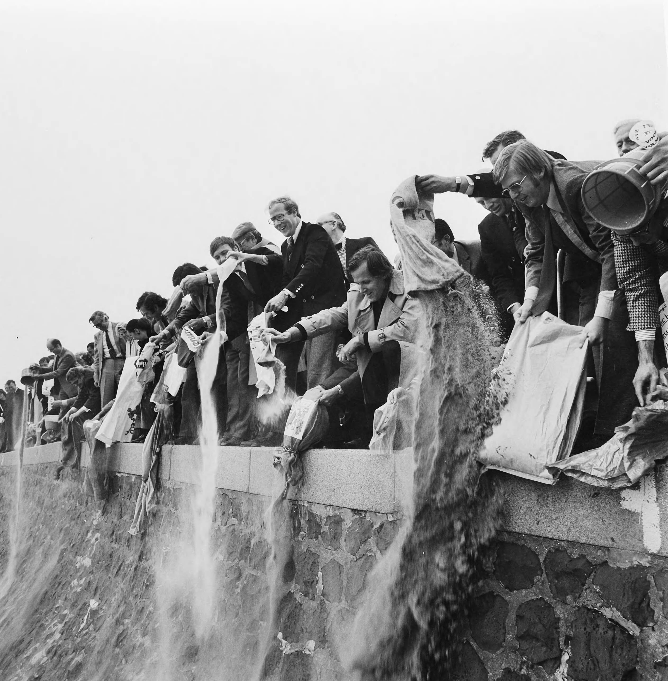 Fotocollectie Anefo — VVV-directeuren brengen zak zand naar jubilerende VVV in Scheveningen; VVV-directeuren storten zand op Scheveningse strand — Foto: Mieremet, Rob / Anefo. Licentie: Set B: Rechtenvrij / Publiek Domein. Bron: Nationaal Archief. http://hdl.handle.net/10648/ac4ade54-d0b4-102d-bcf8-003048976d84