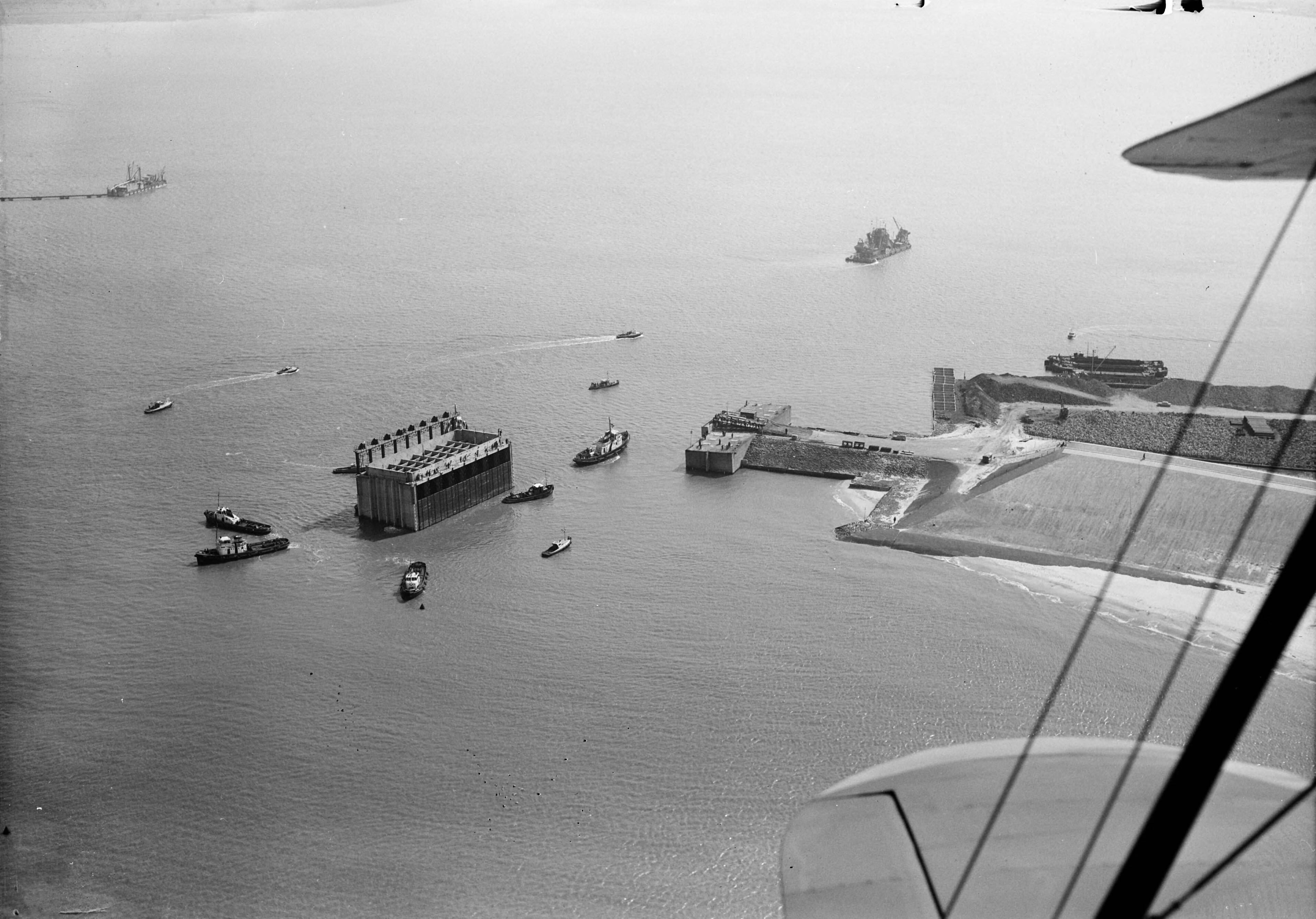 Fotocollectie Anefo — Luchtopnamen. Invaren van caissons in het Veerse Gat — Foto: Slagboom, Anton / Anefo. Licentie: Set B: Rechtenvrij / Publiek Domein. Bron: Nationaal Archief. http://hdl.handle.net/10648/a9d110ee-d0b4-102d-bcf8-003048976d84