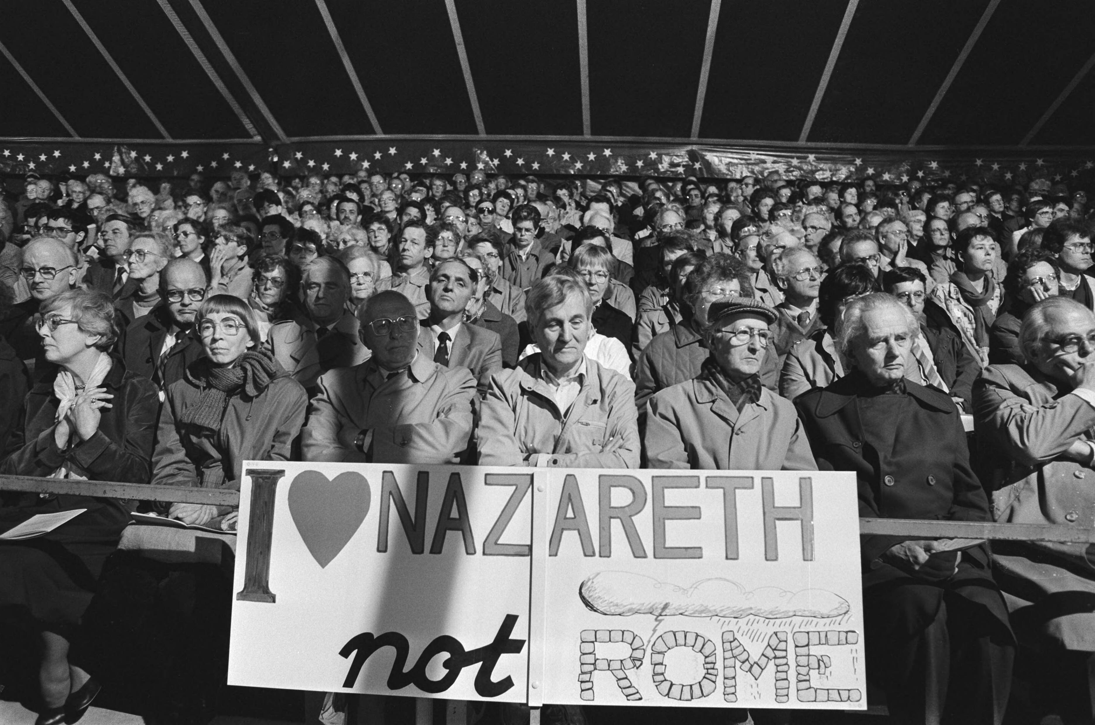 Fotocollectie Anefo — Manifestatie "Het andere gezicht van de kerk" op Malieveld te Den Haag i.v.m. komend Pausbezoek; toehoorders met tekst I love Nazareth, not Rome — Foto: Croes, Rob C. / Anefo. Licentie: Set B: Rechtenvrij / Publiek Domein. Bron: Nationaal Archief. http://hdl.handle.net/10648/ad4670e8-d0b4-102d-bcf8-003048976d84