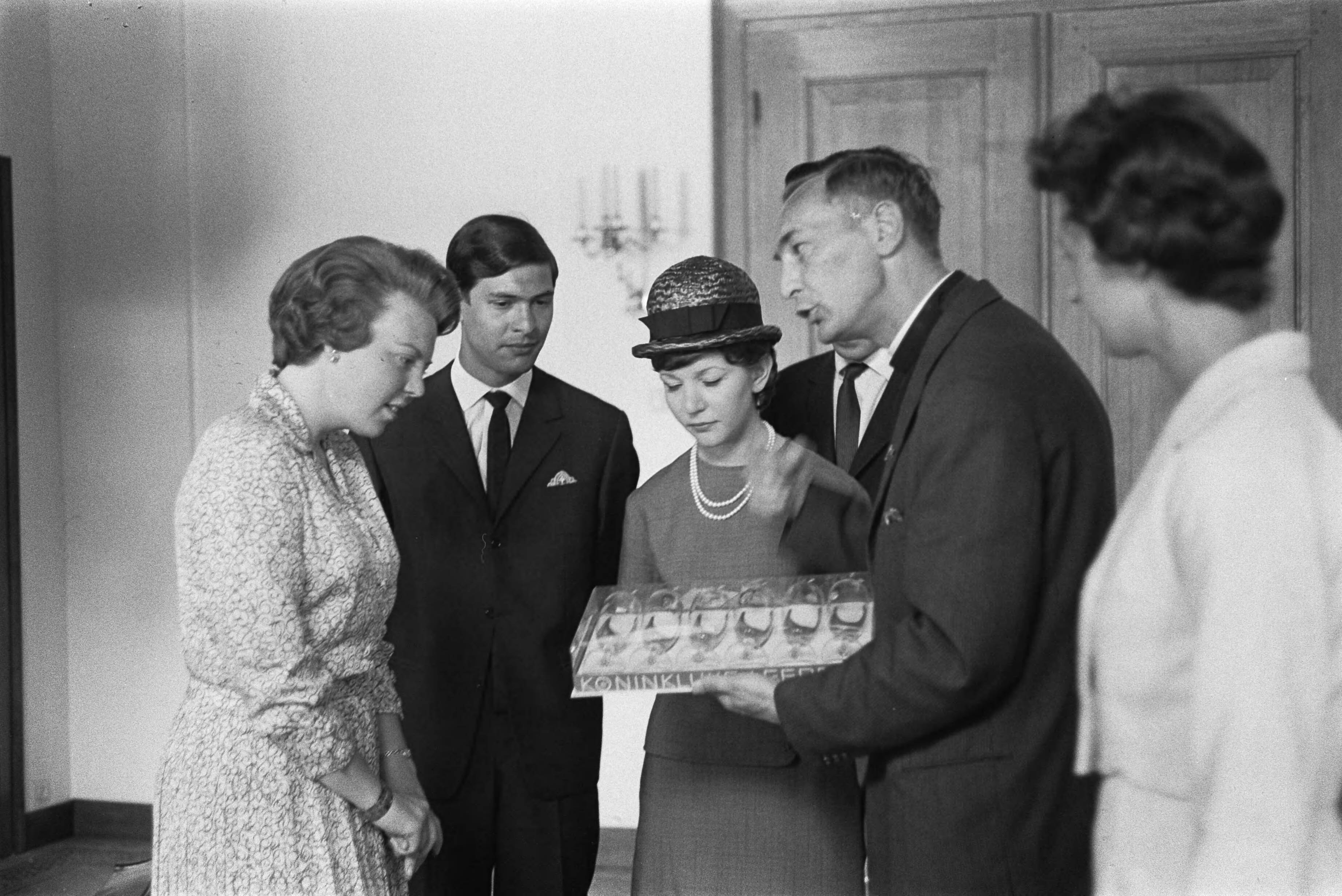 Fotocollectie Anefo — Prinses Beatrix heeft op Kasteel Drakensteyn het actie-comité "Dousadsj" ontvangen, v.l.n.r. Prinses Beatrix , dhr. Rompius, Miss Dousadsj [Adele Rompius-Sadrille], P. van Bueren (deels zichtbaar), pater Werenfried Stokman enmevrouw J. Rigby (penningmeester Europese werkgroep). Pater Stokman biedt de prinses een set glazen aan met de gegraveerde portretten van Nederlandse artiesten, vervaardigd door Koninklijke Leerdam — Foto: Pot, Harry / Anefo. Licentie: Set B: Rechtenvrij / Publiek Domein. Bron: Nationaal Archief. http://hdl.handle.net/10648/aa39380e-d0b4-102d-bcf8-003048976d84