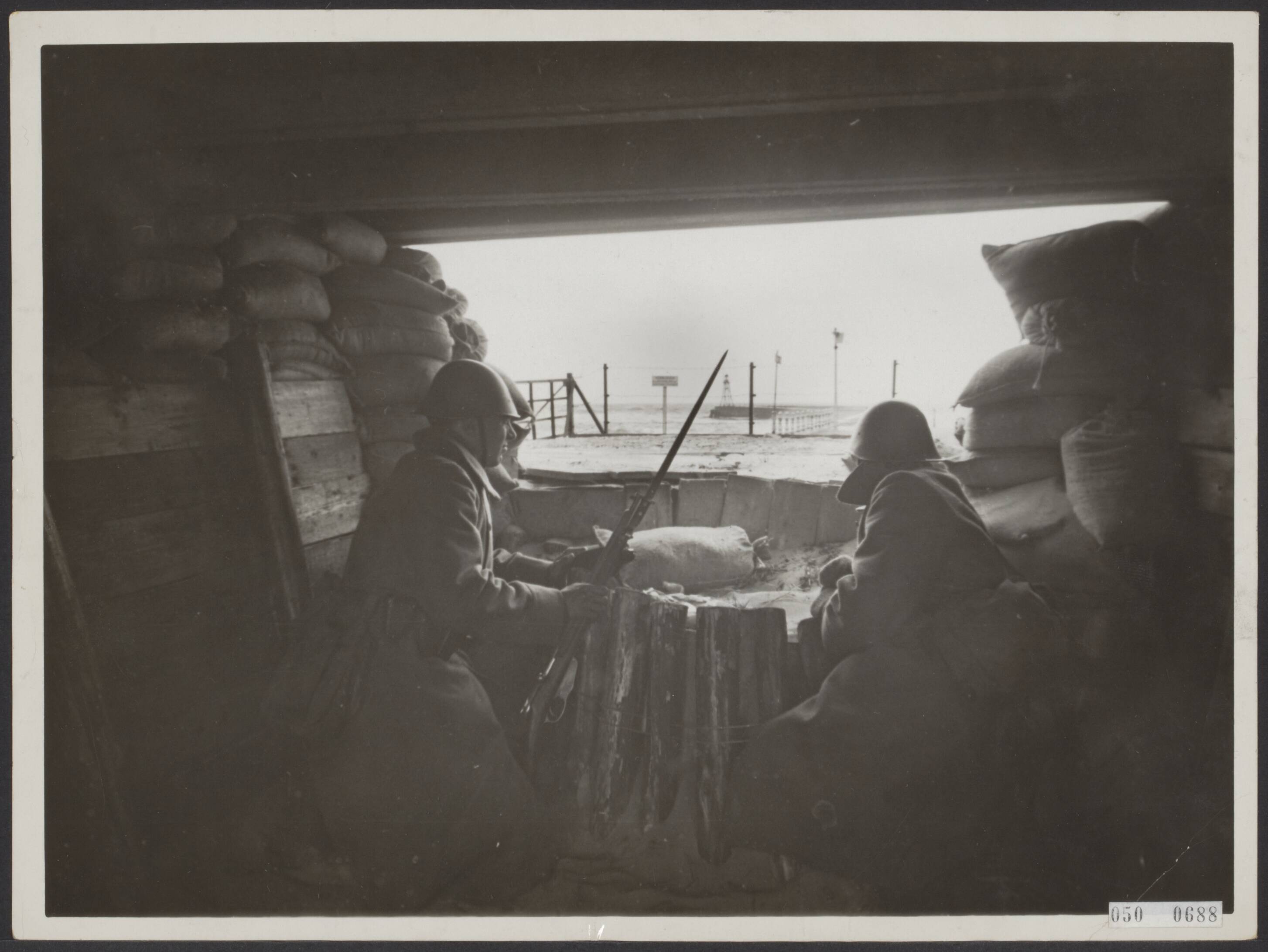 Fotocollectie Elsevier Binnenland — [Mobilsatie 1939?. Twee Nederlandse militairen in een provisorische kazemat bij de Nederlandse kust] — Foto: N.V. Vereenigde Fotobureaux. Licentie: Set B: Rechtenvrij / Publiek Domein. Bron: Nationaal Archief. http://hdl.handle.net/10648/ae038e80-d0b4-102d-bcf8-003048976d84
