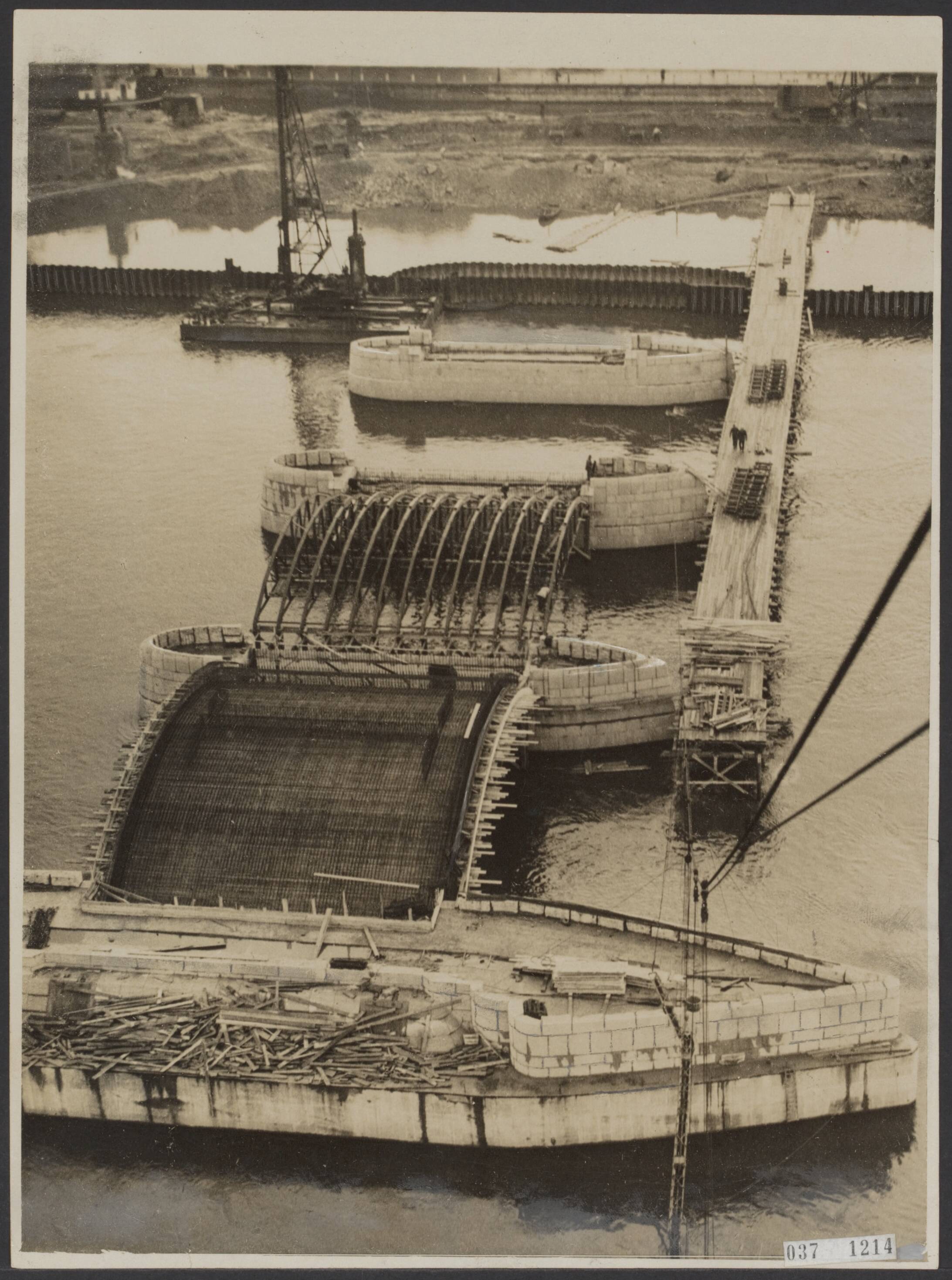 Fotocollectie Elsevier Binnenland — Luchtopname. Maastrichtse bruggenbouw [Aanleg van de Wilhelminabrug over de Maas]. Twee spanningen zijn gereed en op de pijlers, d.w.z. het vlechtwerk daarvan geplaatst. De overbrugging zal nu spoedig een feit zijn. — Foto: R.K. Foto-persbureau "Het Zuiden" / Rechtenvrij. Licentie: Set B: Rechtenvrij / Publiek Domein. Bron: Nationaal Archief. http://hdl.handle.net/10648/adefdd7c-d0b4-102d-bcf8-003048976d84