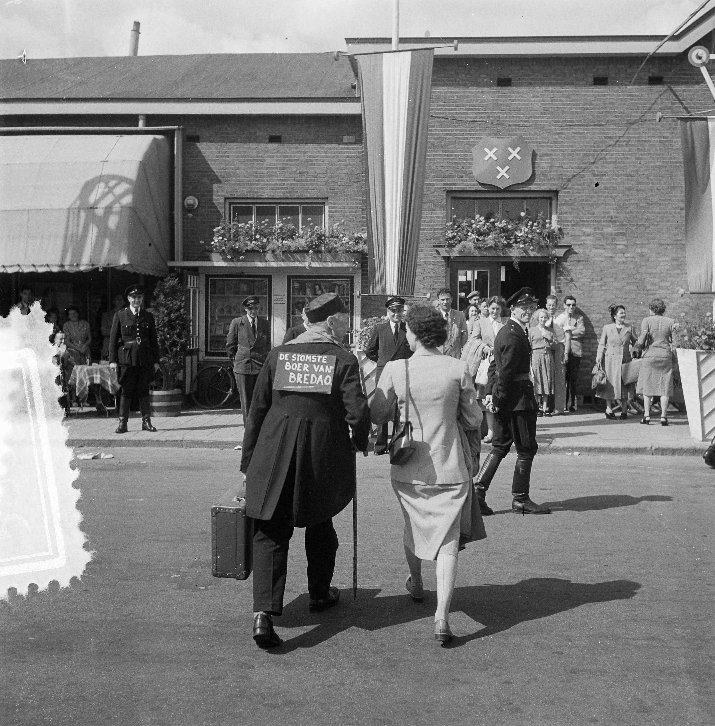 Fotocollectie Anefo — Carnaval Breda. Man met op zijn rug een bord "Stomste boer van Breda" — Foto: Noske, J.D. / Anefo. Licentie: Set B: Rechtenvrij / Publiek Domein. Bron: Nationaal Archief. http://hdl.handle.net/10648/a9106772-d0b4-102d-bcf8-003048976d84