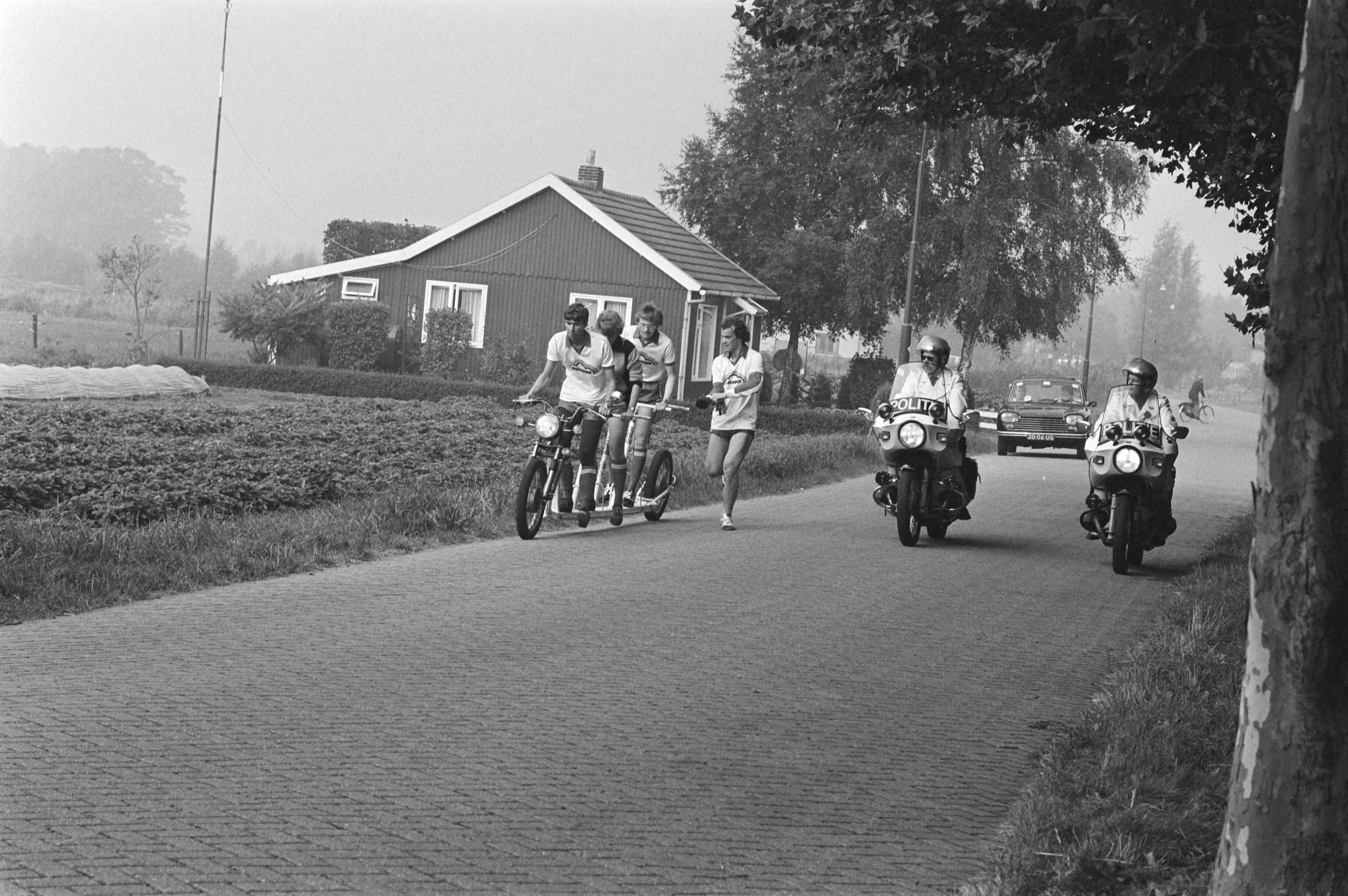 Autoped-tour naar Utrecht in Breda gestart (vierde keer) — Een vierpersoons autoped tijdens de autoped-tour van Breda naar Utrecht onderweg begeleid door twee motorrijders — Foto: Bogaerts, Rob / Anefo. Licentie: Set B: Rechtenvrij / Publiek Domein. Bron: Nationaal Archief. http://hdl.handle.net/10648/ad032f9a-d0b4-102d-bcf8-003048976d84
