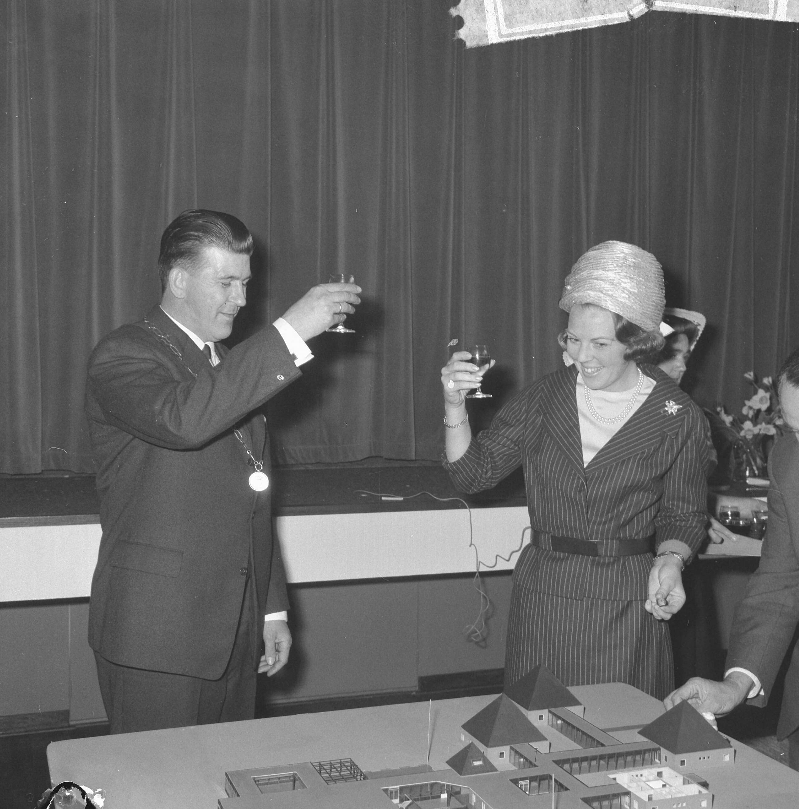 Fotocollectie Anefo — Prinses Beatrix was aanwezig bij de eerste steenlegging voor het jongerenontmoetingscentrum "Het Zilveren Schor" nabij Arnemuiden. Burgemeester A. Hack toost met prinses Beatrix. Voor hen de maquette van het gebouw, een ontwerp van architect Onno Greiner — Foto: Nijs, Jac. de / Anefo. Licentie: Set B: Rechtenvrij / Publiek Domein. Bron: Nationaal Archief. http://hdl.handle.net/10648/aaa1c8e2-d0b4-102d-bcf8-003048976d84