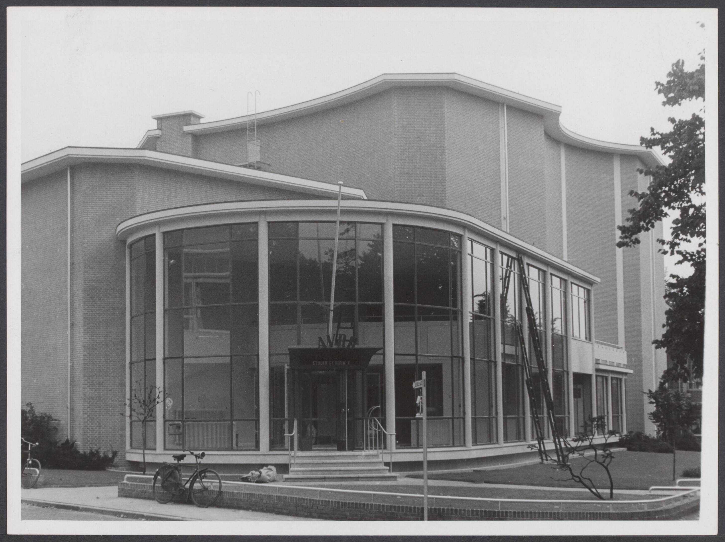 AVRO (Algemene Vereniging Radio Omroep). Studio-gebouwen, exterieur en interieur - Nederland — In Hilversum zijn de nieuwe AVRO-studio's gereed gekomen die door voorzitter W. Vogt zullen worden geopend. De glazenwassers hebben hun intocht gehouden. het gebouw is weldra gereed voor de ontvangst der gasten — Foto: Stapf Bilderdienst. Licentie: Set B: Rechtenvrij / Publiek Domein. Bron: Nationaal Archief. http://hdl.handle.net/10648/4ce1faac-d0bd-b5ea-9d2e-51450b32f083