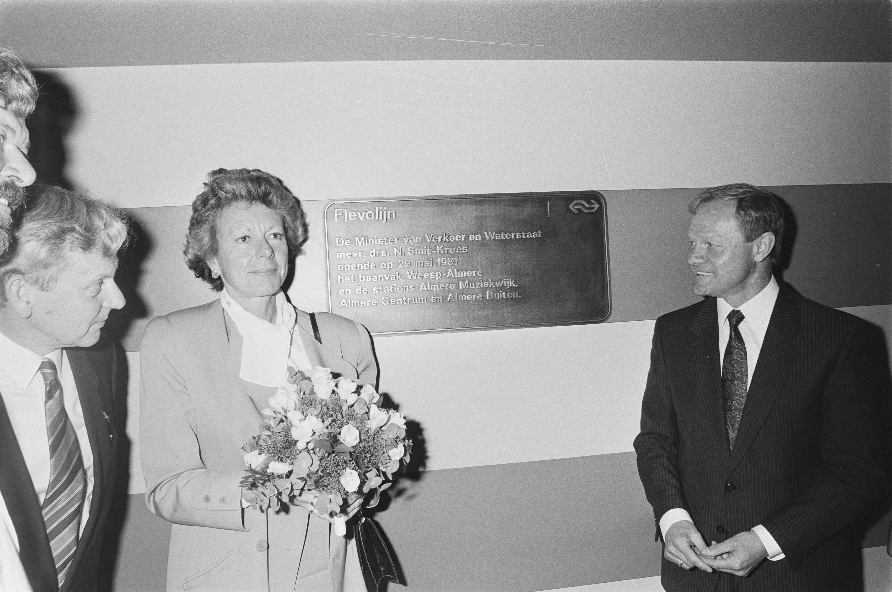 Fotocollectie Anefo — Officiele opening Flevolijn traject Weesp-Almere; minister Smit-Kroes en president-directeur Ploeger van de NS — Foto: Molendijk, Bart / Anefo. Licentie: Set B: Rechtenvrij / Publiek Domein. Bron: Nationaal Archief. http://hdl.handle.net/10648/ad60dcc6-d0b4-102d-bcf8-003048976d84