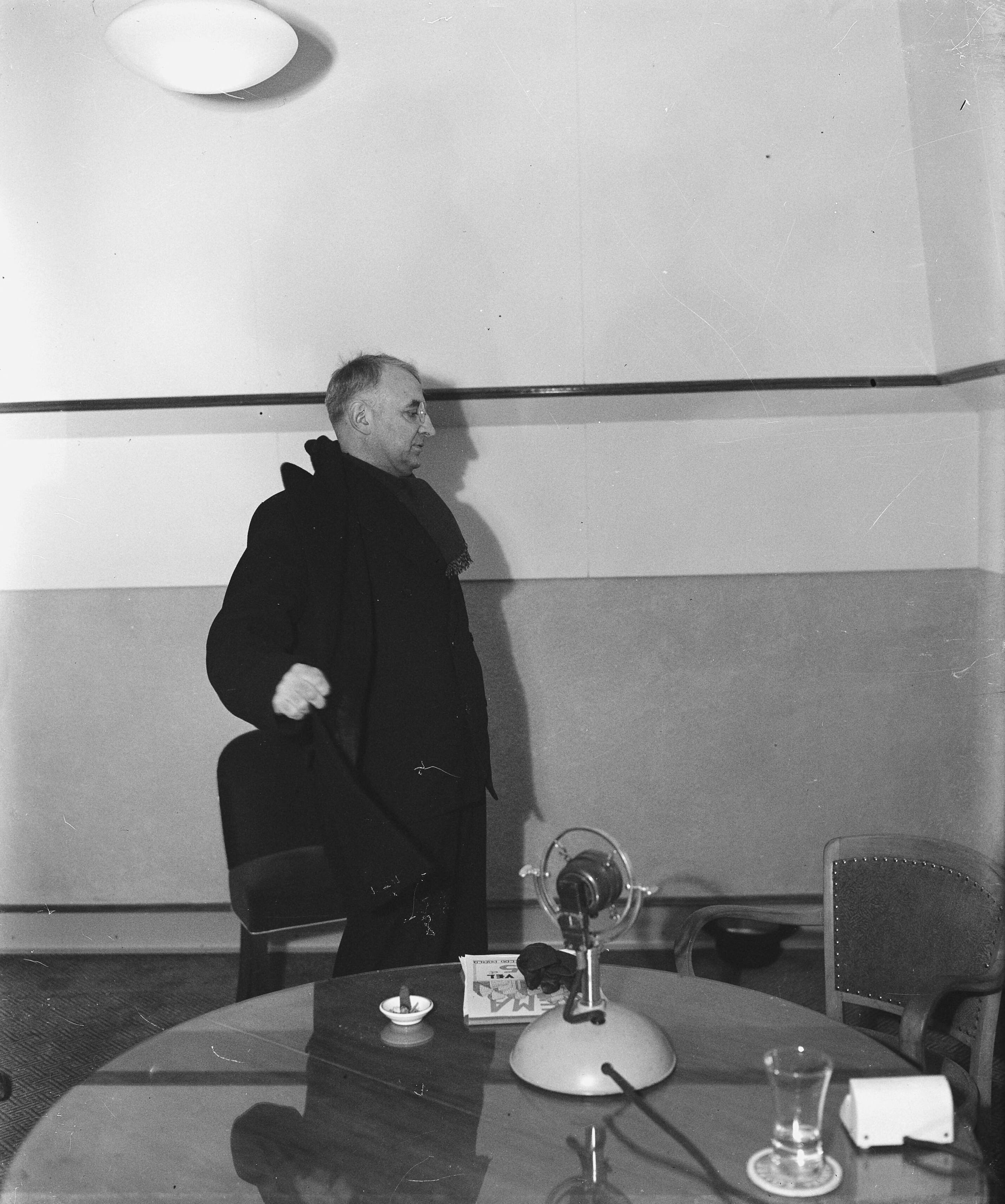 Pater Henri de Greeve houdt zijn radiotoespraak — In de studio van de KRO — Foto: Raucamp, Koos / Anefo. Licentie: Set B: Rechtenvrij / Publiek Domein. Bron: Nationaal Archief. http://hdl.handle.net/10648/a896ea6e-d0b4-102d-bcf8-003048976d84