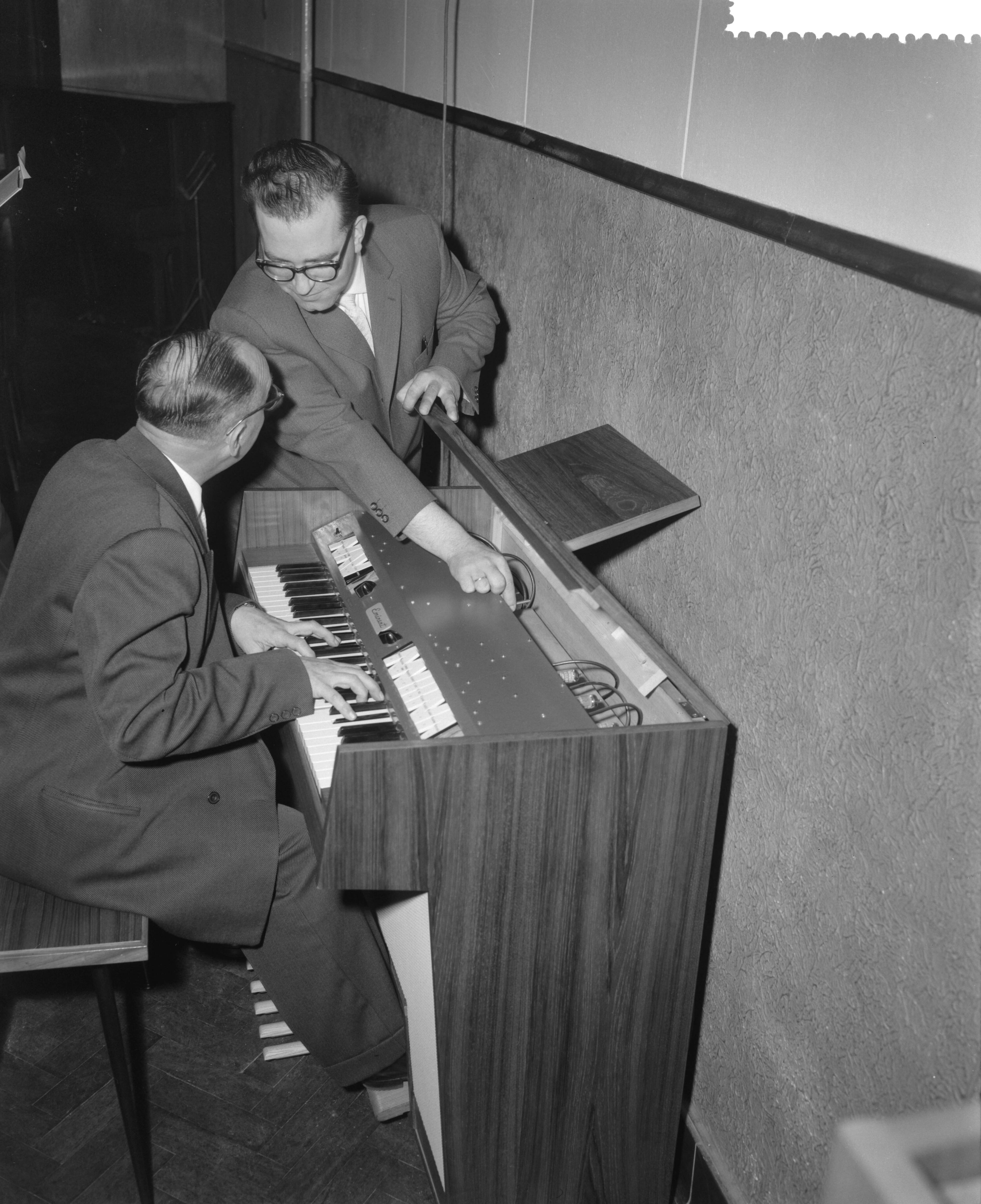 Fotocollectie Anefo — Demonstratie van nieuw elektronisch huisorgel te Bodegraven. Ontwerper Hans Versteegt geeft toelichting, terwijl Pierre Palla speelt — Foto: Behrens, Herbert F. / Anefo. Licentie: Set B: Rechtenvrij / Publiek Domein. Bron: Nationaal Archief. http://hdl.handle.net/10648/a9c10da2-d0b4-102d-bcf8-003048976d84