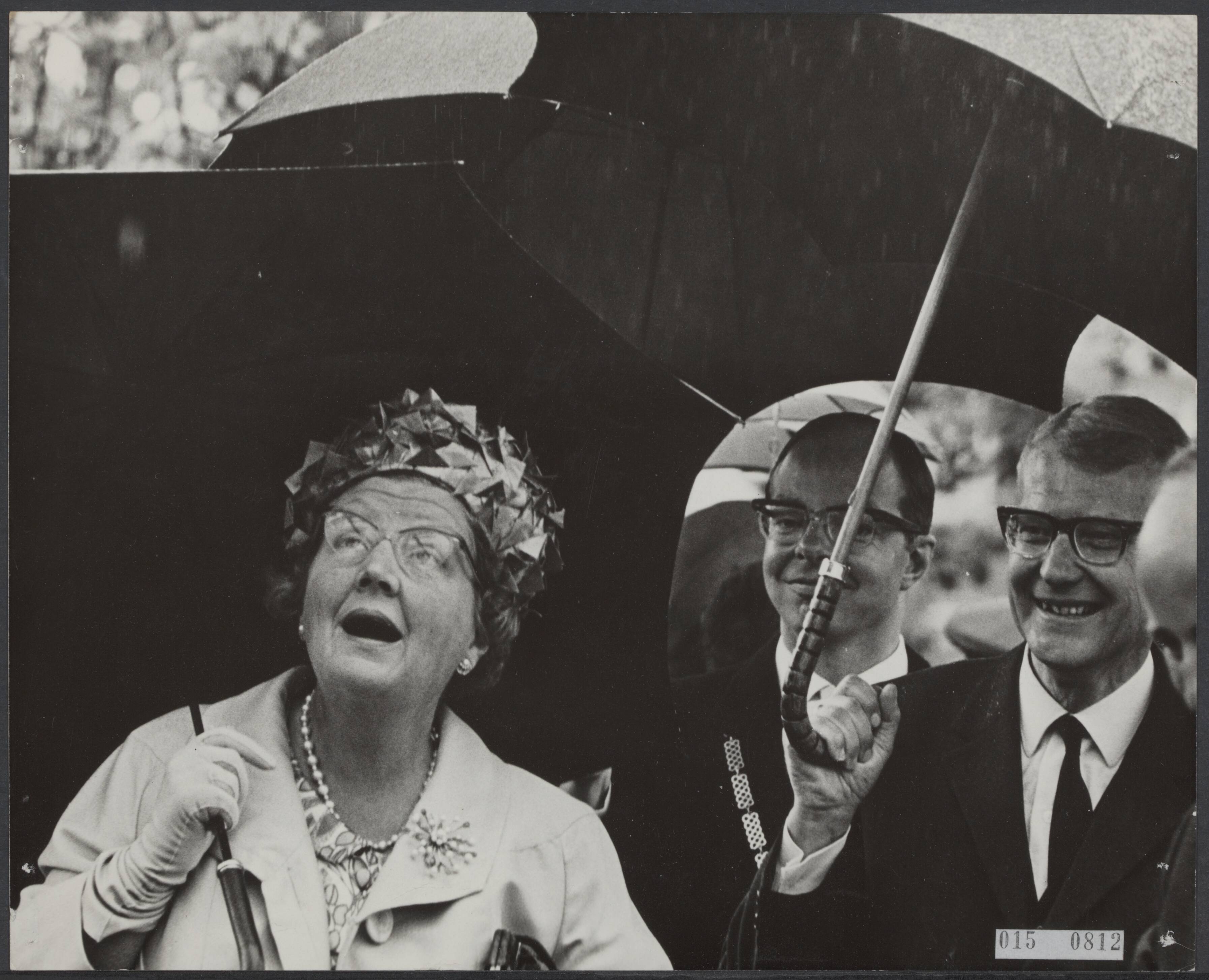 Fotocollectie Elsevier Binnenland — Bezoek van koningin Juliana aan enkele Zuid-Hollandse gemeenten. Tijdens een korte bezichtiging van de tuinen in het Sierteeltcentrum van Boskoop werd het gezelschap verrast door de regen — Foto: Koch, Eric / Anefo. Licentie: Set B: Rechtenvrij / Publiek Domein. Bron: Nationaal Archief. http://hdl.handle.net/10648/adb63b3a-d0b4-102d-bcf8-003048976d84
