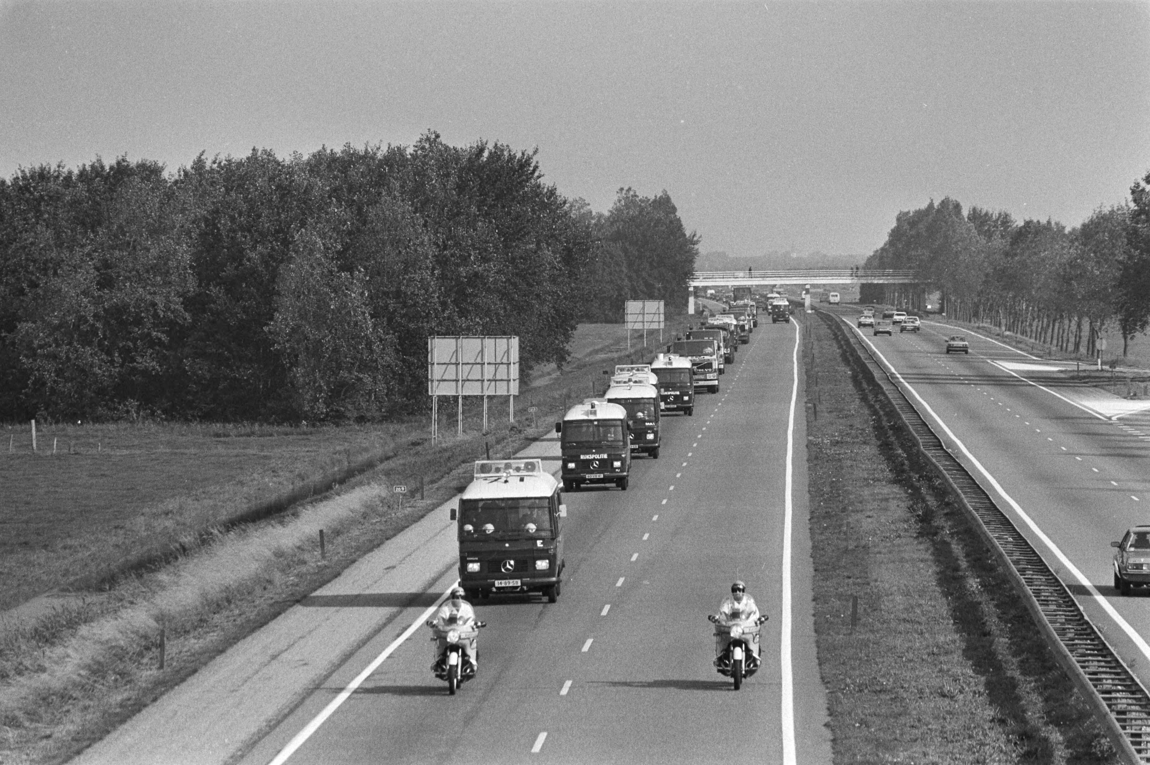 Transport van radio-aktief afval van het Energieonderzoek Centrum Nederland in Petten — Het transport van radioactief afval uit Petten onder politiebegeleiding op weg naar IJmuiden — Foto: Antonisse, Marcel / Anefo. Licentie: Set B: Rechtenvrij / Publiek Domein. Bron: Nationaal Archief. http://hdl.handle.net/10648/ad02cb0e-d0b4-102d-bcf8-003048976d84