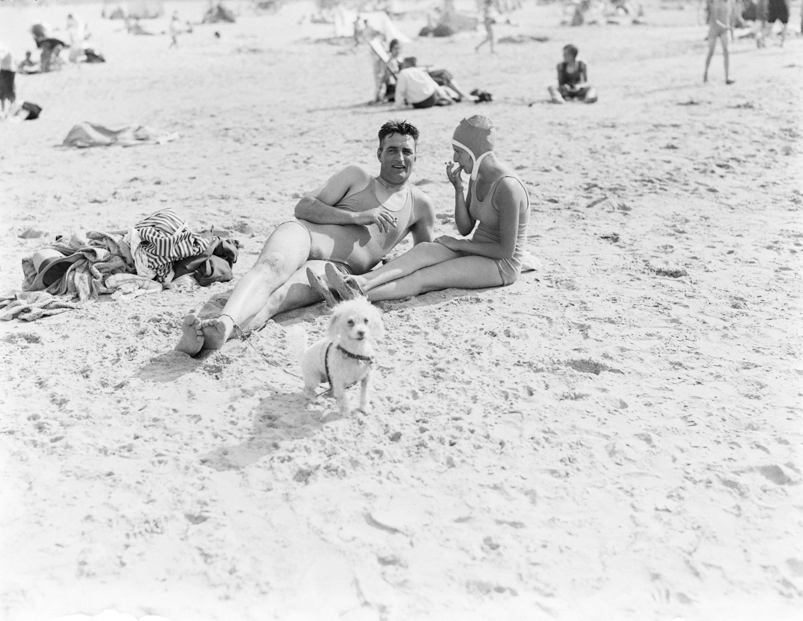 Strandtaferelen Scheveningen — Rokende man en vrouw op het strand, met hond — Foto: Poll, Willem van de. Licentie: Set B: Rechtenvrij / Publiek Domein. Bron: Nationaal Archief. http://hdl.handle.net/10648/aea863a6-d0b4-102d-bcf8-003048976d84