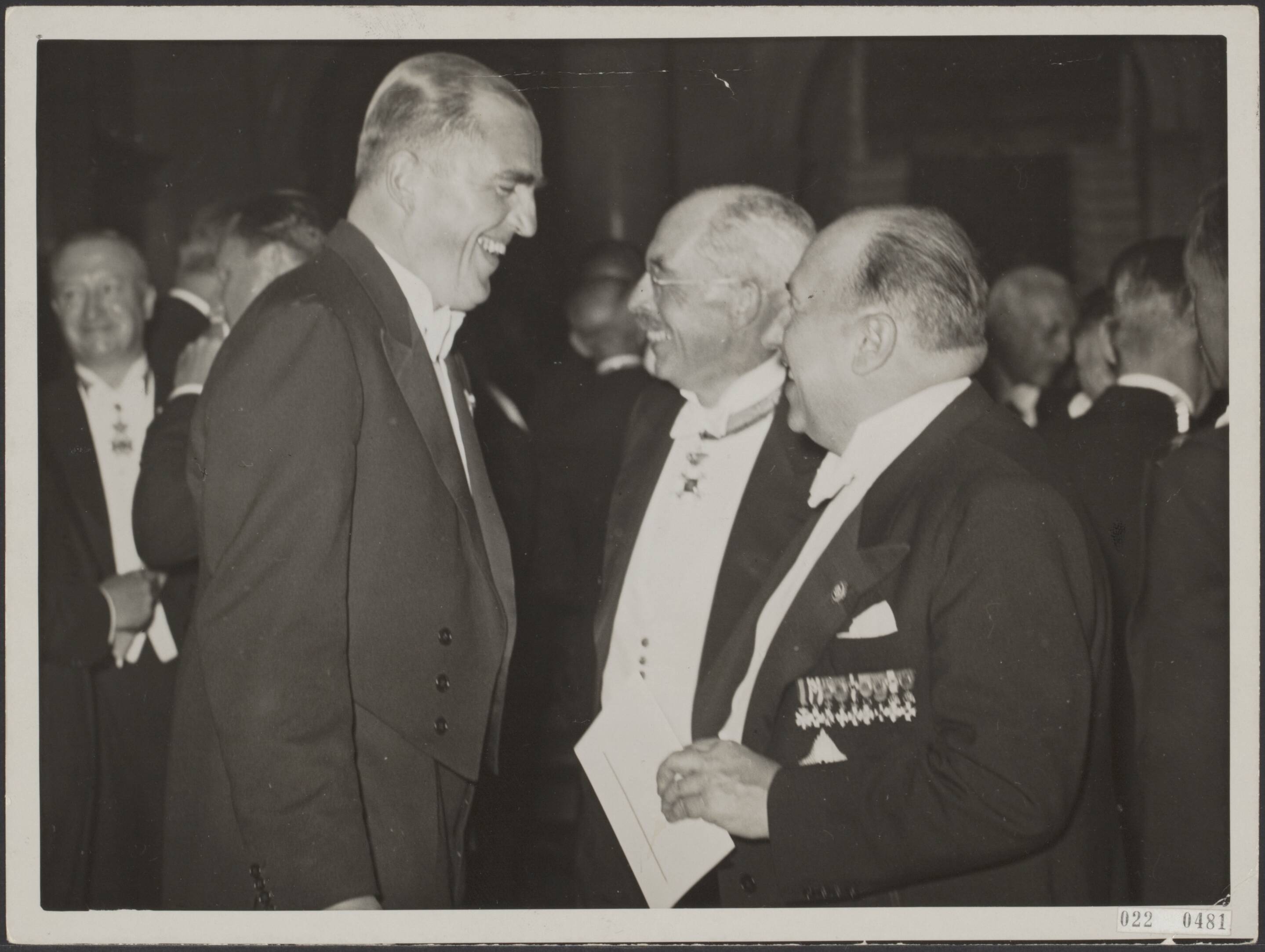 Fotocollectie Elsevier Binnenland — Hedenavond heeft de minister van Economische Zaken, mr. M.P.L. Steenberghe (links) zijn Duitse collega, dr. Walter Funk (rechts), een diner aangeboden in kasteel Oud Wassenaar. In het midden jhr. mr. dr. H.A. van Karnebeek, Commissaris der Koningin in de provincie Zuid-Holland — Foto: N.V. Polygoon. Licentie: Set B: Rechtenvrij / Publiek Domein. Bron: Nationaal Archief. http://hdl.handle.net/10648/add23a10-d0b4-102d-bcf8-003048976d84