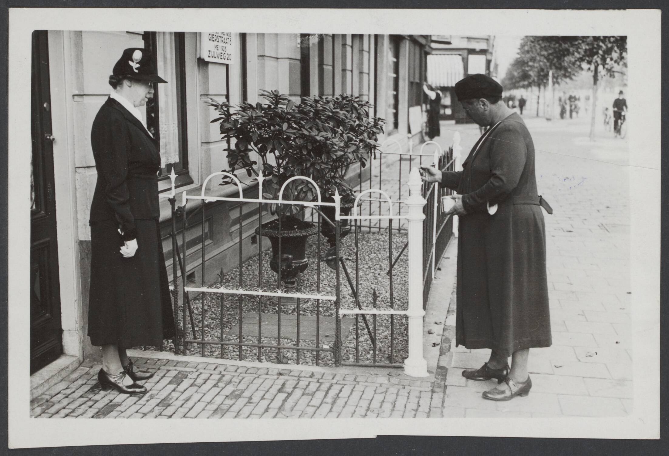 BVD. Bescherming bevolking, enz. Nederland. — Haarlem, 5 september 1940. Een voorbeeld dat navolging verdient. Een dame in Haarlem schildert haar tuinhekje, dat ver in de straat uitsteekt, wit, zodat men niet meer de kans kan lopen en tijdens de verduistering tegen aan te lopen en zich te bezeren, op de kleren te scheuren — Foto: N.V. Polygoon. Licentie: Set B: Rechtenvrij / Publiek Domein. Bron: Nationaal Archief. http://hdl.handle.net/10648/5dd3cd9a-399a-9a48-ee3d-da5588df00b3