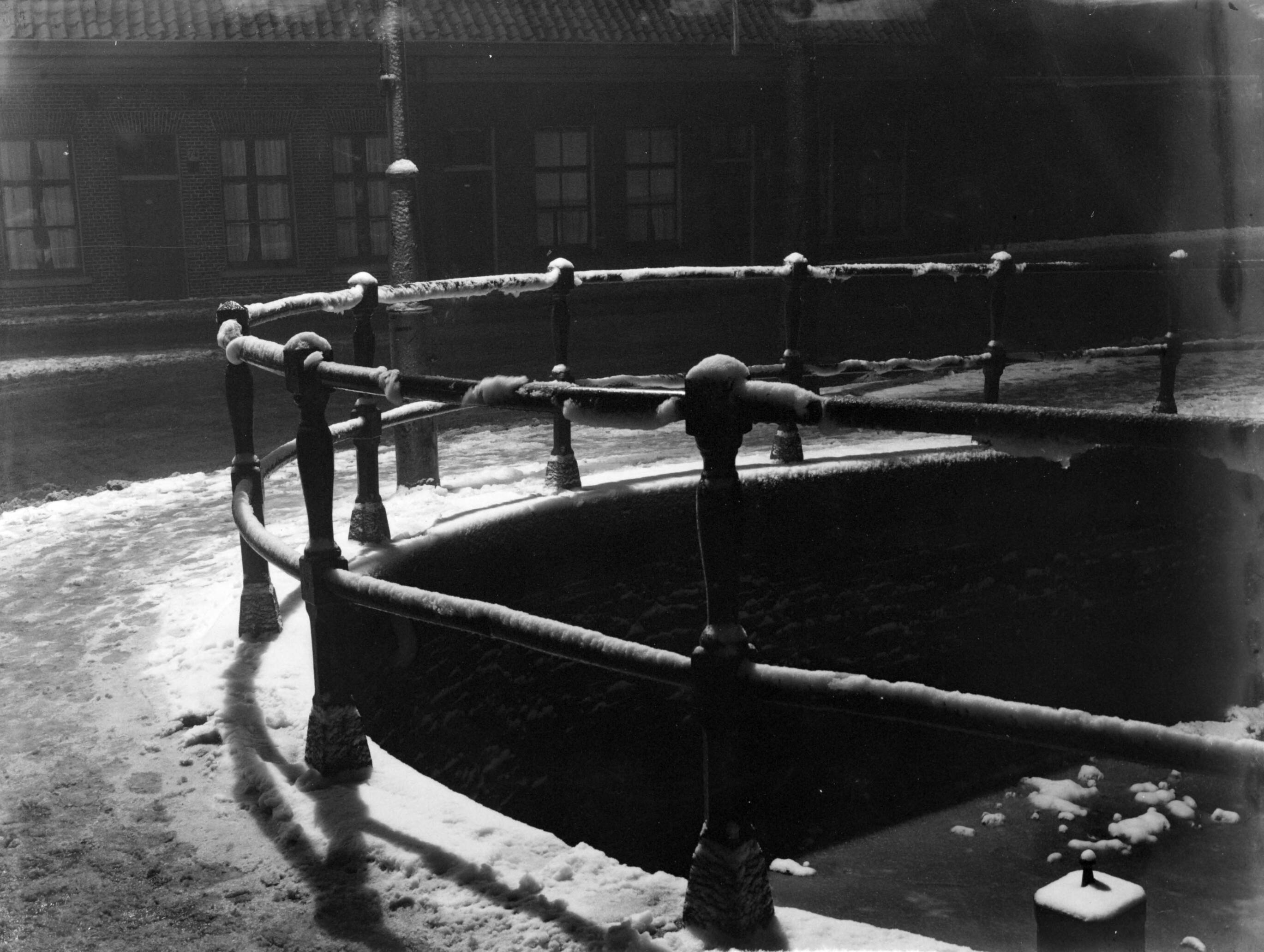 Fotocollectie Van de Poll — Besneeuwde straten en hekwerk rond een dichtgevroren gracht in het lamplicht in Haarlem — Foto: Poll, Willem van de. Licentie: Set B: Rechtenvrij / Publiek Domein. Bron: Nationaal Archief. http://hdl.handle.net/10648/ae9be4a0-d0b4-102d-bcf8-003048976d84
