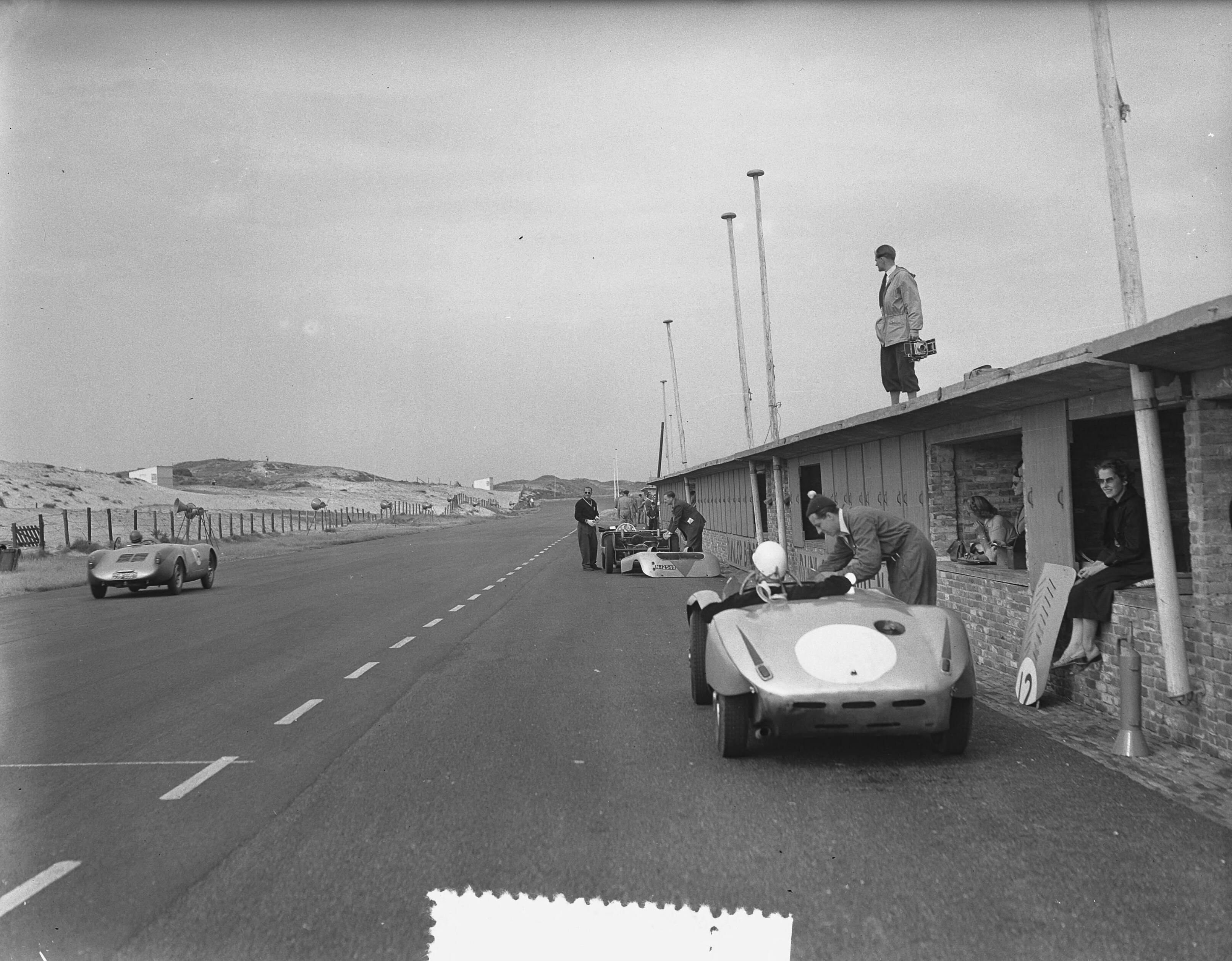 Fotocollectie Anefo — Trainingsdag sportwagenraces Zandvoort. Fotograaf staat op dack van paddock langs de pitstraat — Foto: Bilsen, Joop van / Anefo. Licentie: Set B: Rechtenvrij / Publiek Domein. Bron: Nationaal Archief. http://hdl.handle.net/10648/a927c23c-d0b4-102d-bcf8-003048976d84