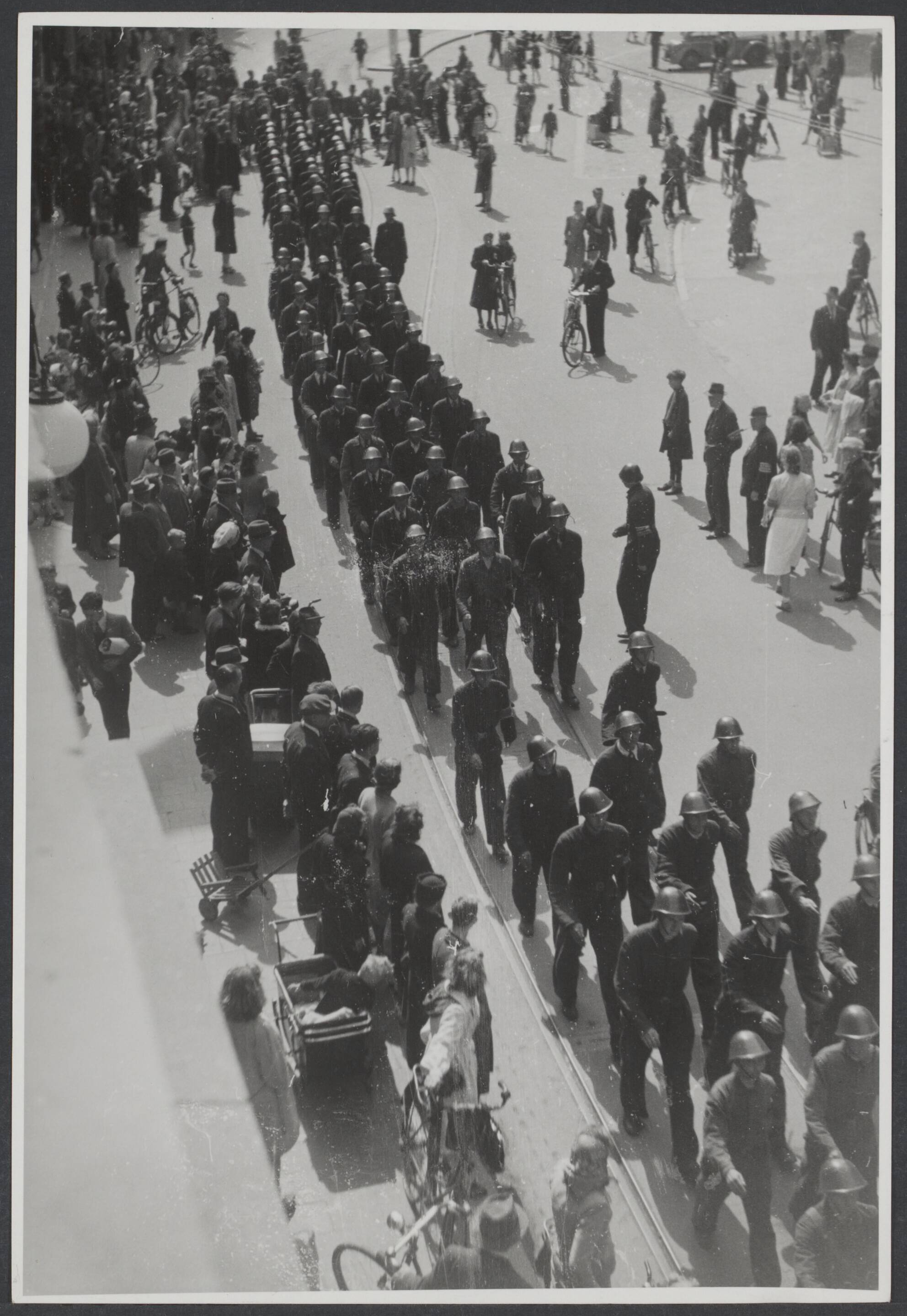 Bevrijding 's Gravenhage (Den Haag) — Een defilé van de Binnenlandse Strijdkrachten (BS), in blauwe overall en oranje band om de arm, tijdens de intocht der Canadezen te Den Haag, — Foto: Wal, J.Th. A. van der / Spaarnestad. Licentie: Set B: Rechtenvrij / Publiek Domein. Bron: Nationaal Archief. http://hdl.handle.net/10648/9e4cc41a-9e39-a674-c60d-5763cc1ddf60