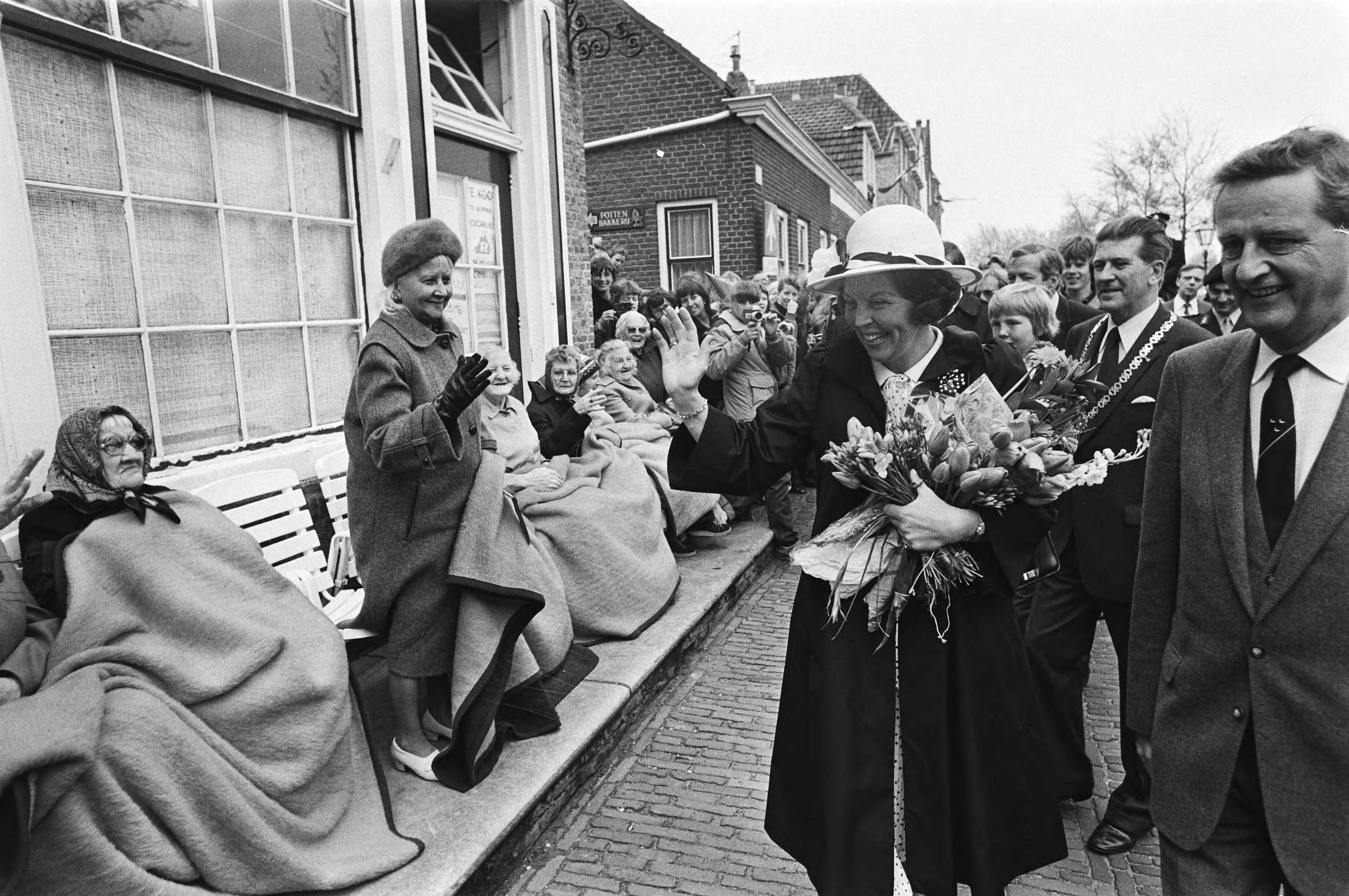 Fotocollectie Anefo — Viering Koninginnedag in Veere, Koningin Beatrix zwaait naar bejaarden die dik ingepakt langs de route zaten — Foto: Bogaerts, Rob / Anefo. Licentie: Set B: Rechtenvrij / Publiek Domein. Bron: Nationaal Archief. http://hdl.handle.net/10648/acfaaab4-d0b4-102d-bcf8-003048976d84