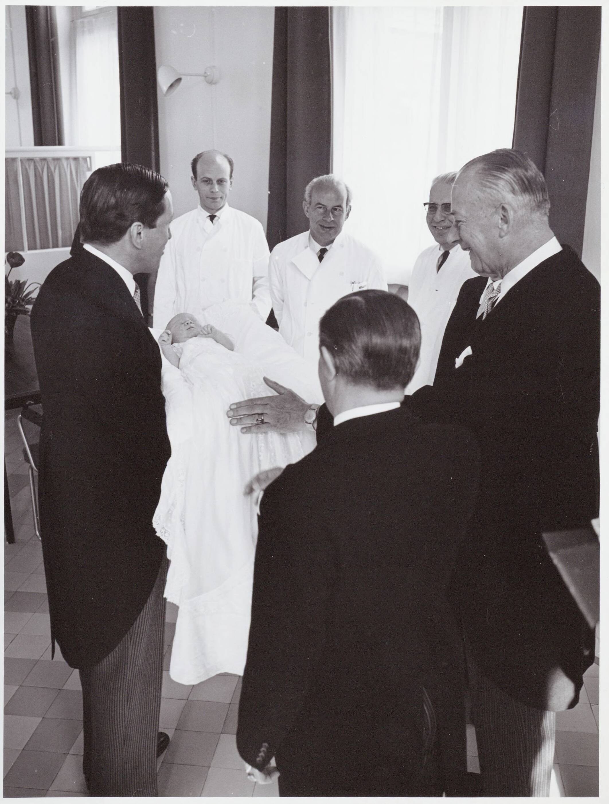 Fotocollectie RVD / Koninklijk Huis — Prins Claus toont de baby prins Willem-Alexander aan de doktoren in het Academisch Ziekenhuis Utrecht op 2 mei 1967 — Foto: Nationaal Foto Persbureau / RVD. Licentie: Set B: Rechtenvrij / Publiek Domein. Bron: Nationaal Archief. http://hdl.handle.net/10648/afaf3338-d0b4-102d-bcf8-003048976d84