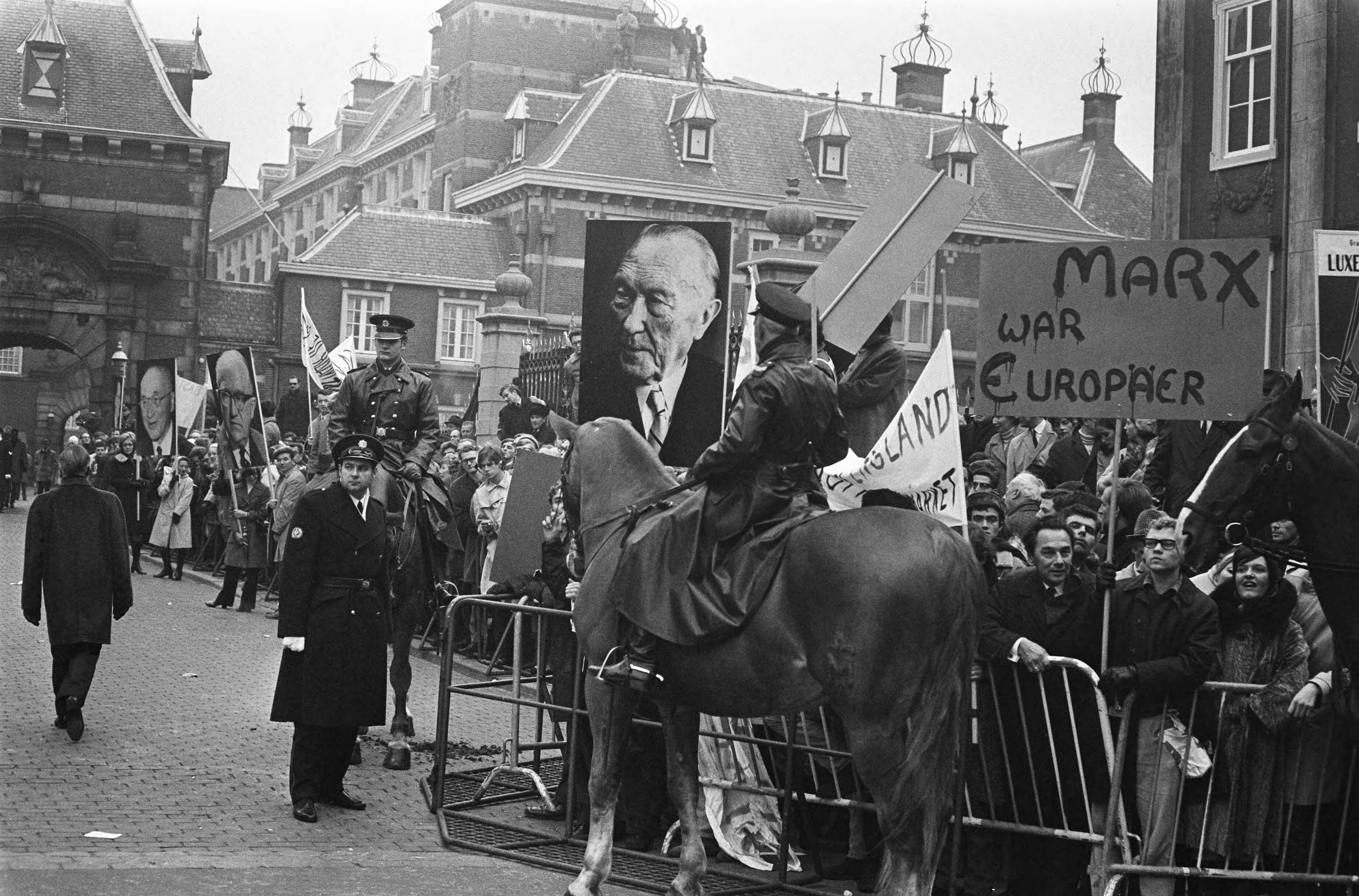Fotocollectie Anefo — Demonstraties bij het Binnenhof Den Haag tijdens EEG- conferentie. Demonstranten met borden onder andere Adenau — Foto: Verhoeff, Bert / Anefo. Licentie: Set B: Rechtenvrij / Publiek Domein. Bron: Nationaal Archief. http://hdl.handle.net/10648/ab84255c-d0b4-102d-bcf8-003048976d84