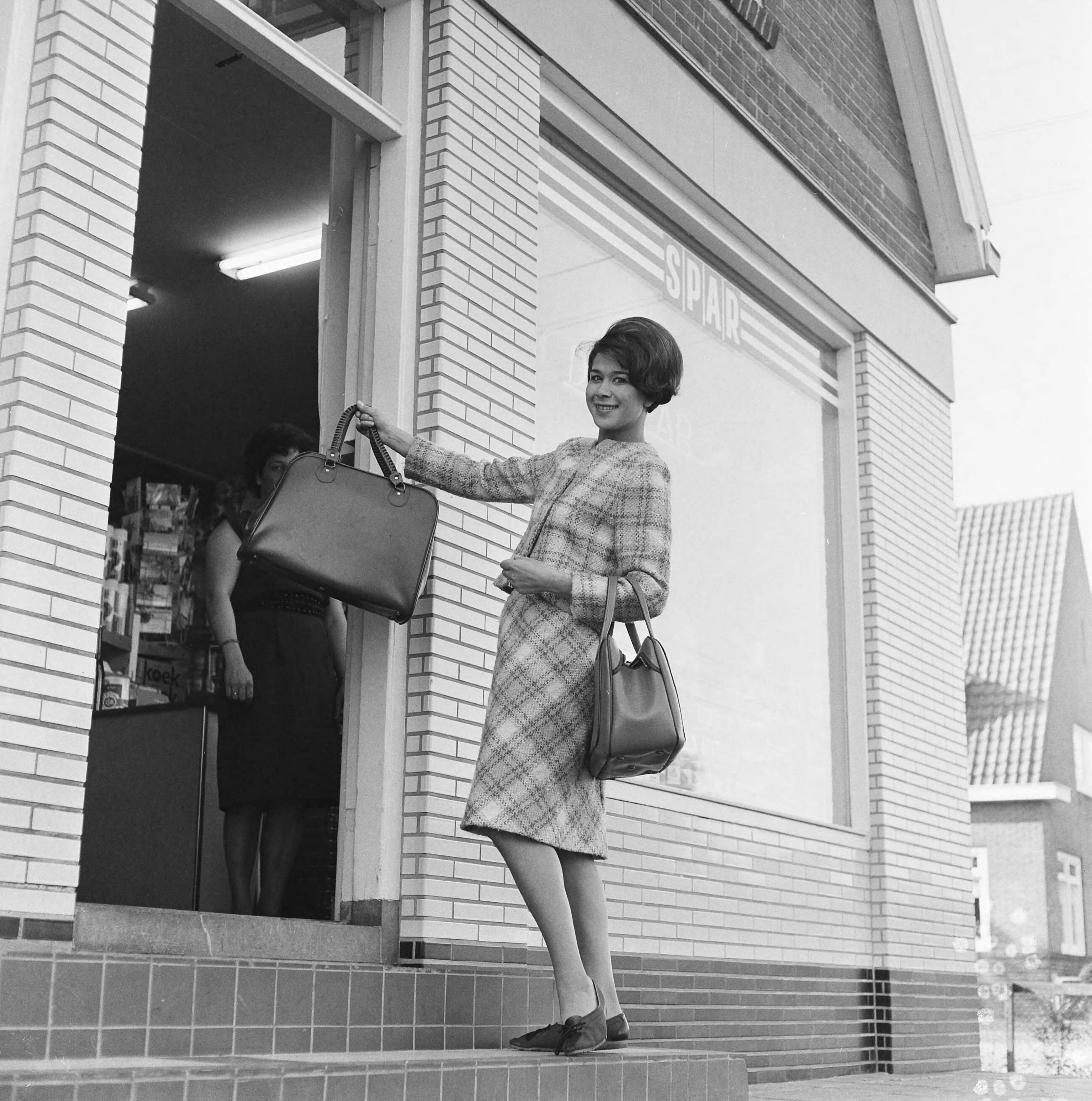 Anneke Grönloh in Vinkeveen — Anneke Grönloh terwijl zij een SPAR supermarkt gaat betreden. Zij toont een tas (opdracht Veenhoven) — Foto: Kroon, Ron / Anefo. Licentie: Set B: Rechtenvrij / Publiek Domein. Bron: Nationaal Archief. http://hdl.handle.net/10648/aac79eb4-d0b4-102d-bcf8-003048976d84